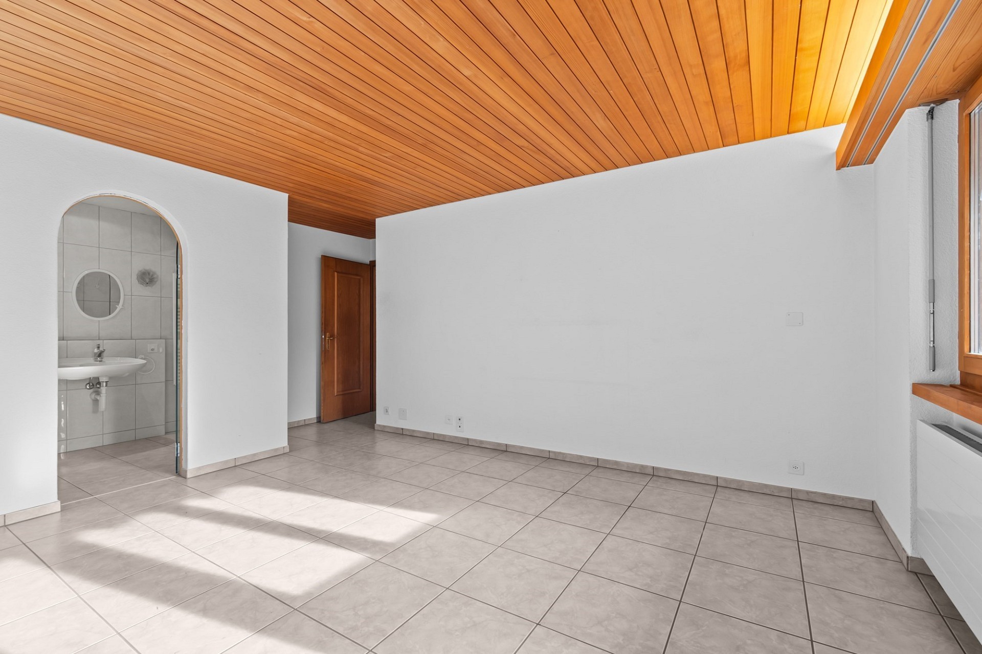 Heller Innenraum mit Fliesenboden und Holzdecke
