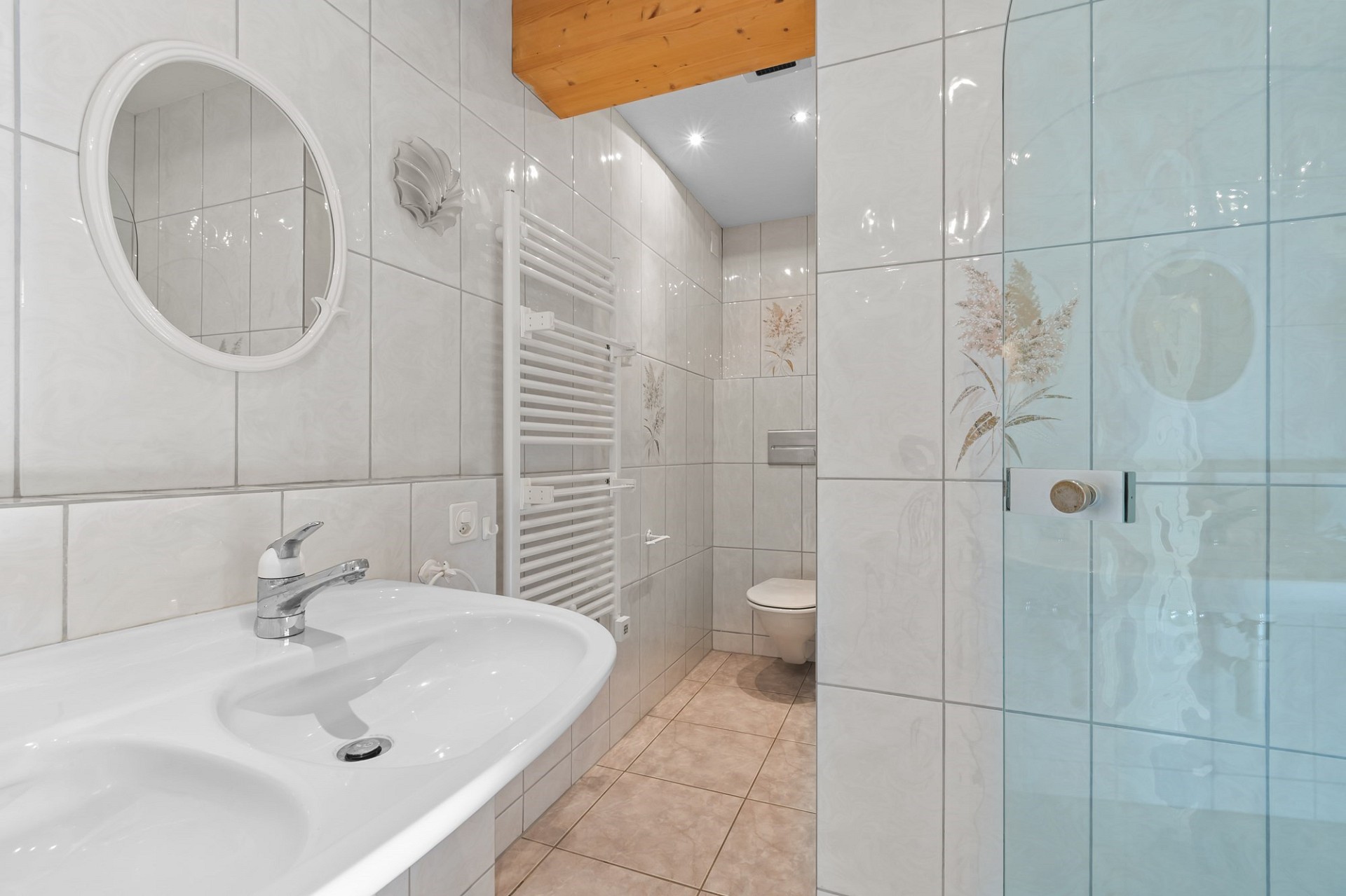 Hell gefliestes Badezimmer mit Waschbecken und Dusche