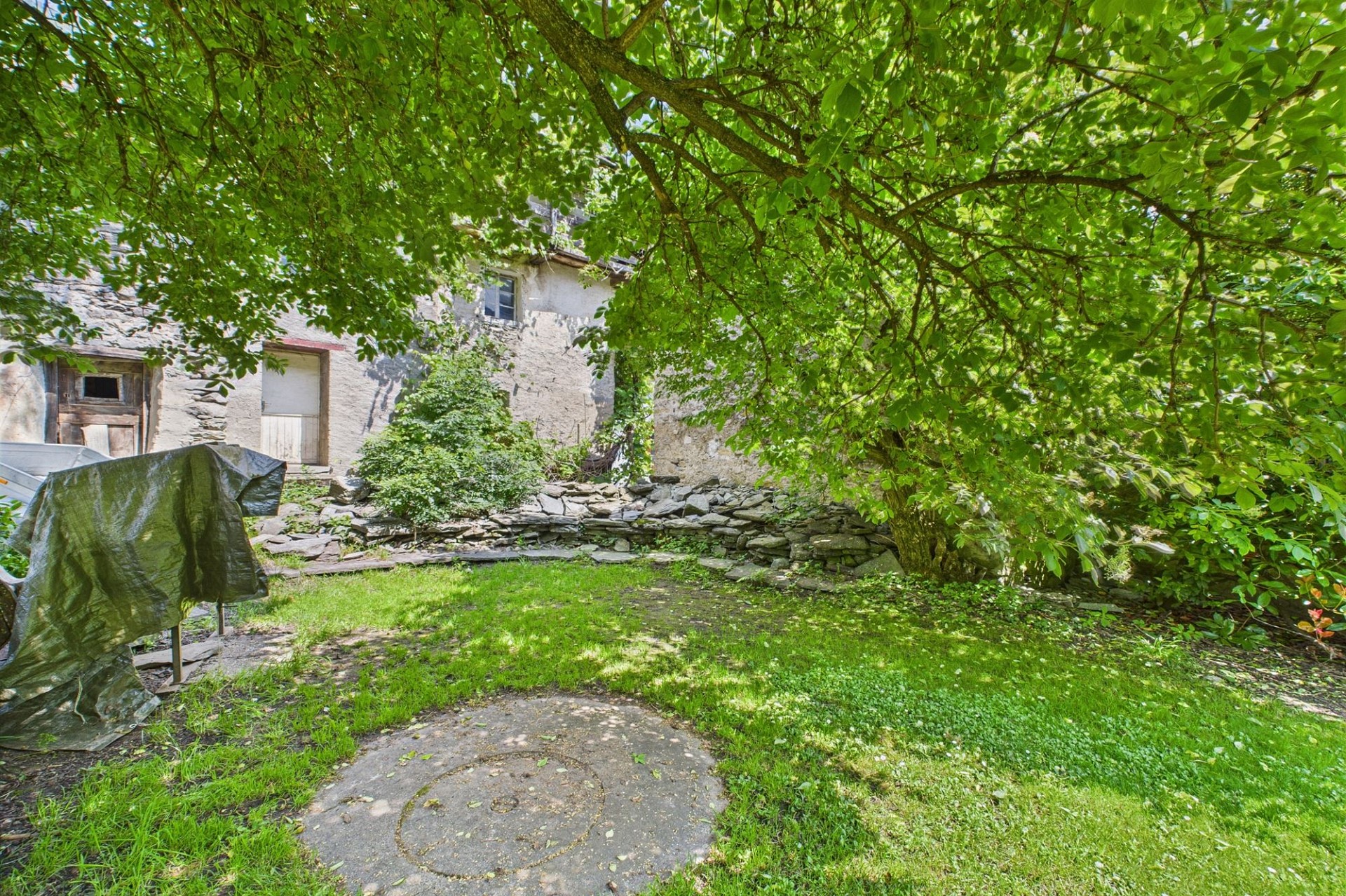 Verwilderter Garten mit altem Steinhaus