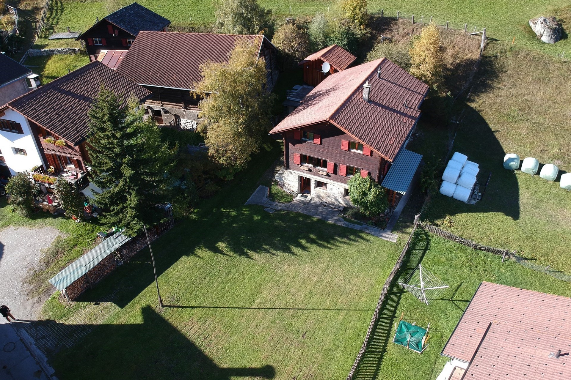 Luftaufnahme eines ländlichen Hofensembles mit Chalets und großen Gärten