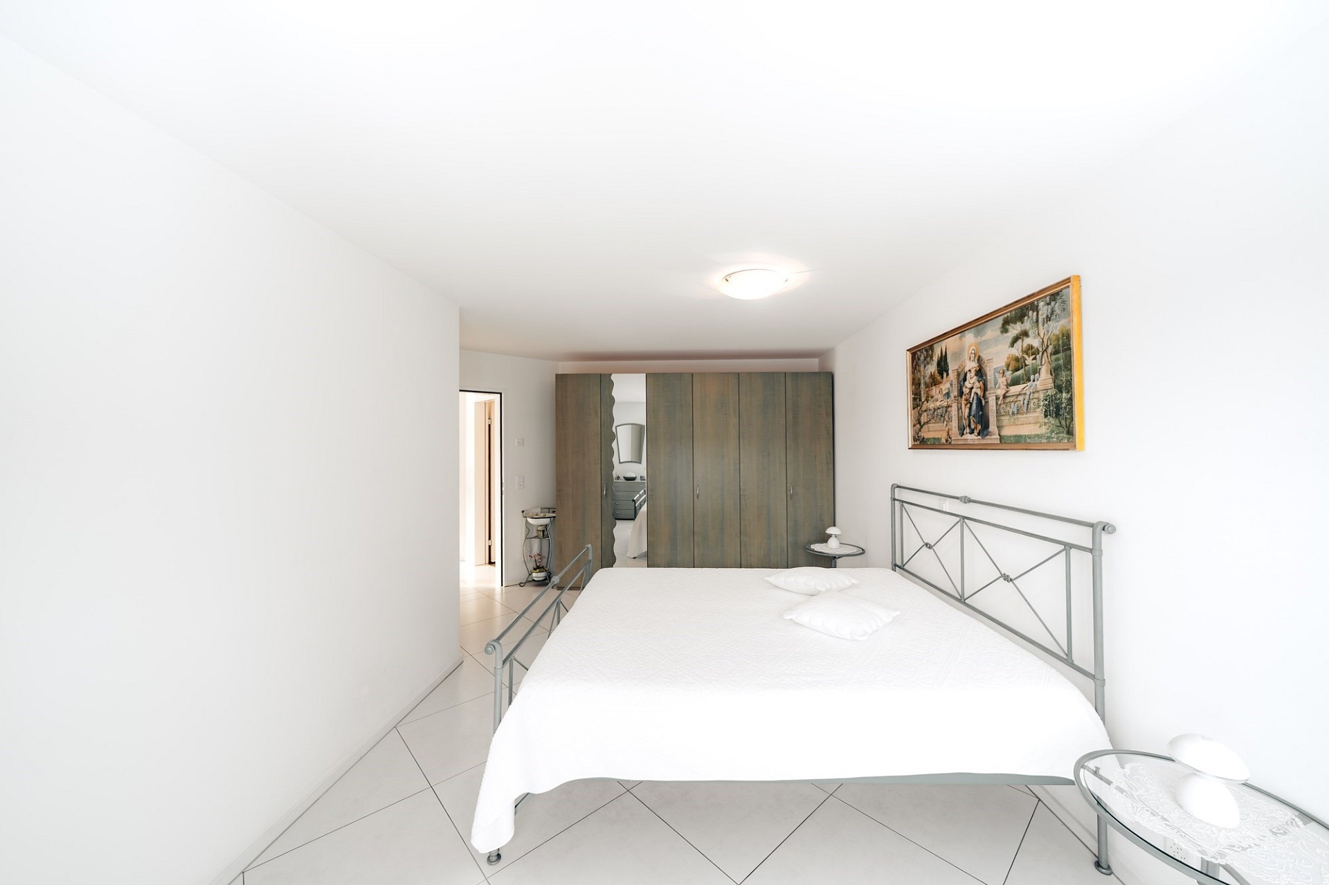 Helles Schlafzimmer mit Metallbett und Einbauschrank