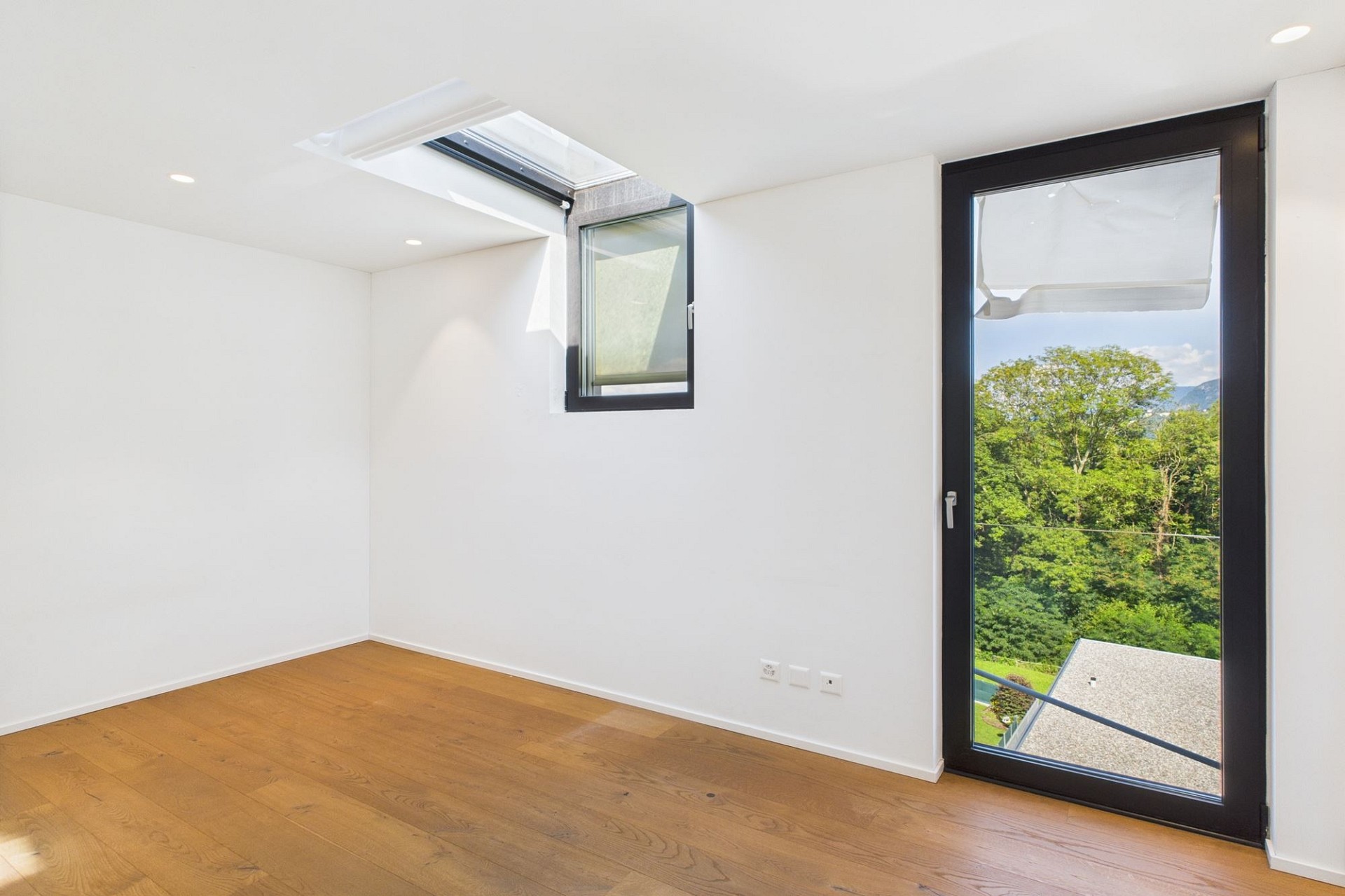 Helles leeres Zimmer mit Dachfenster und Balkontür
