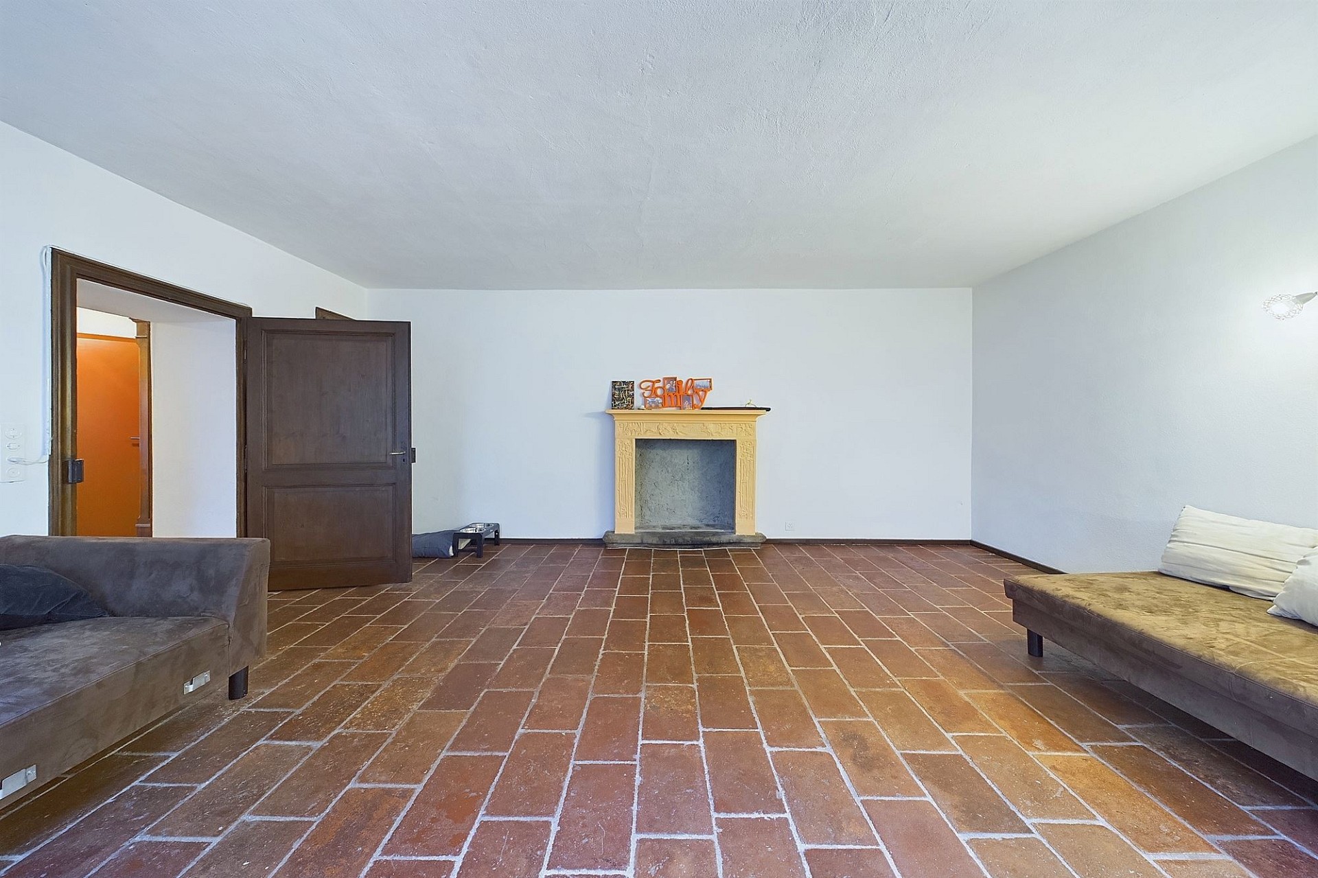 Wohnzimmer mit Kamin und Terrakotta-Boden