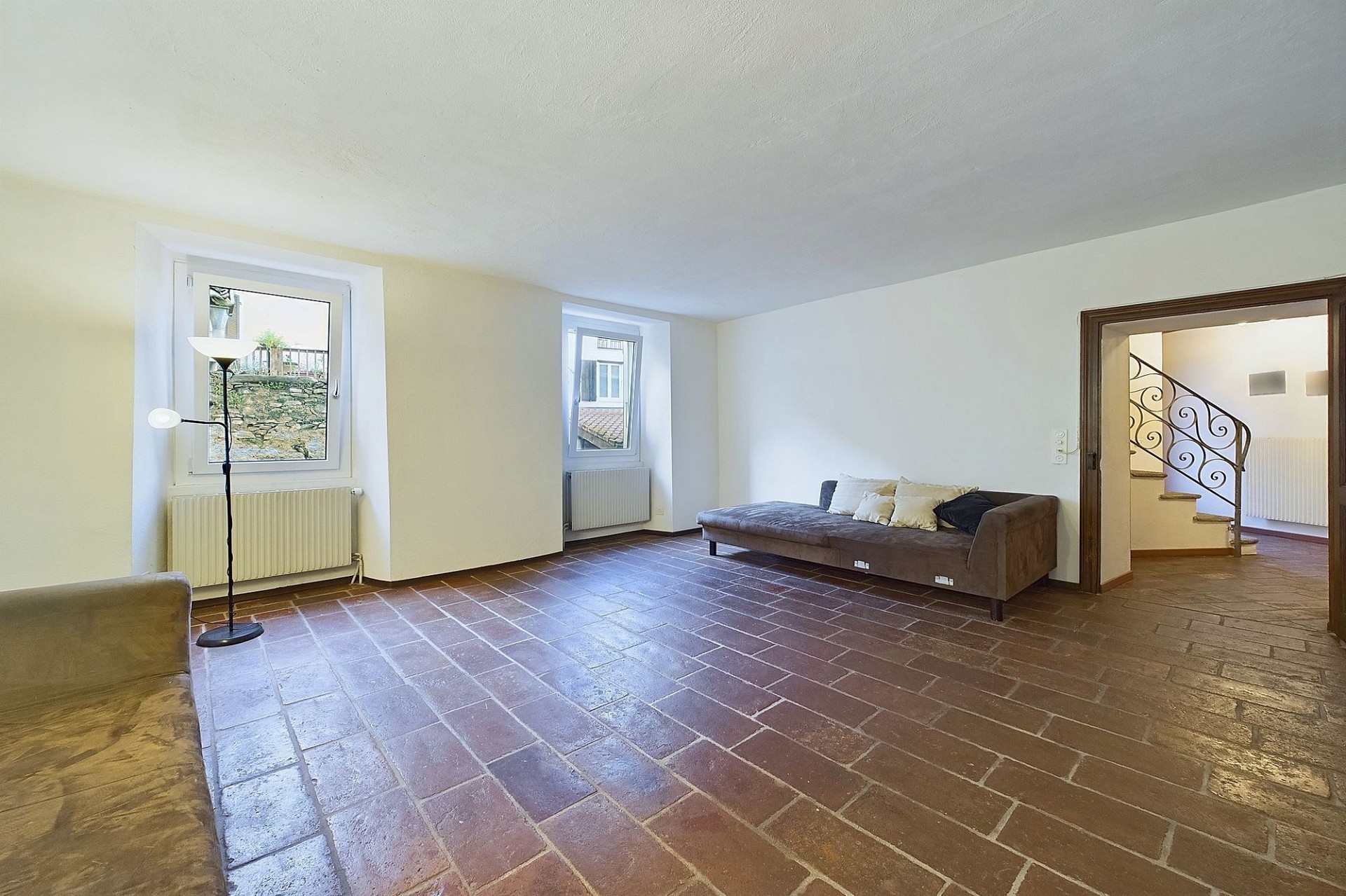 Großer Wohnraum mit Terrakottaboden und Treppenblick