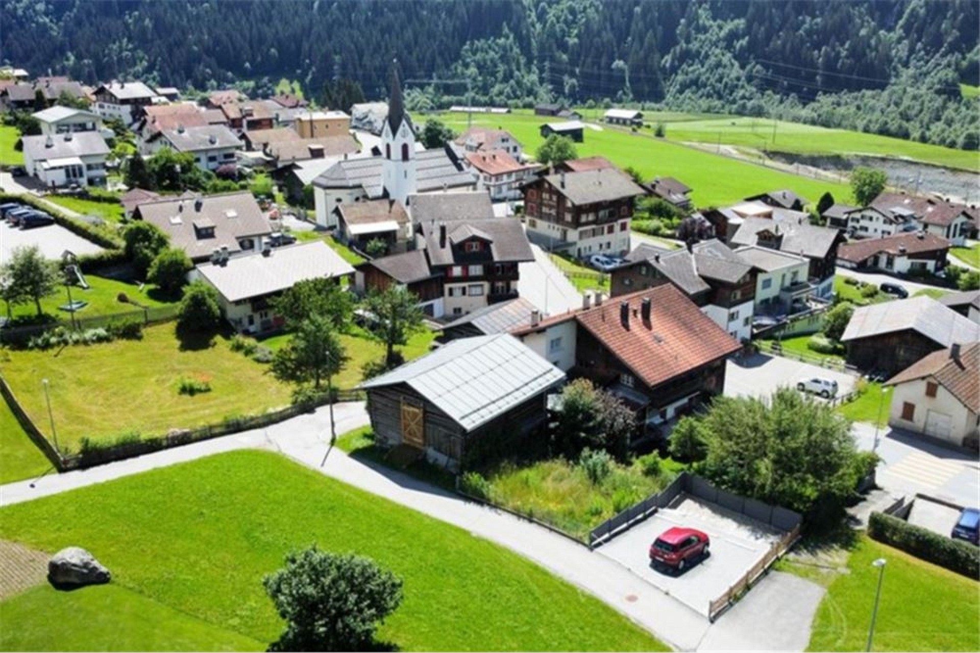 Luftaufnahme eines Dorfes in alpiner Landschaft