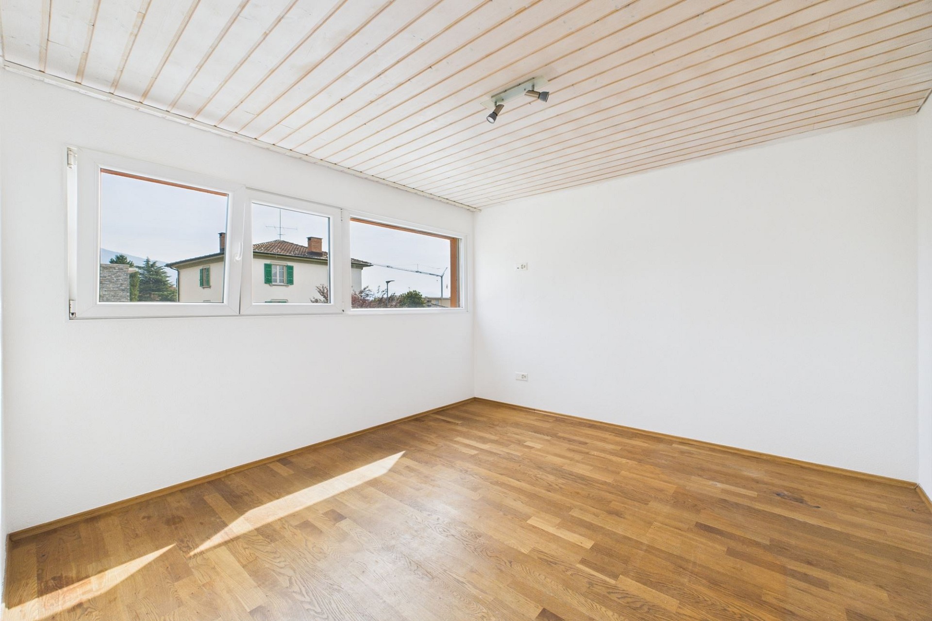 Heller leerer Raum mit Holzfußboden und Fenstern
