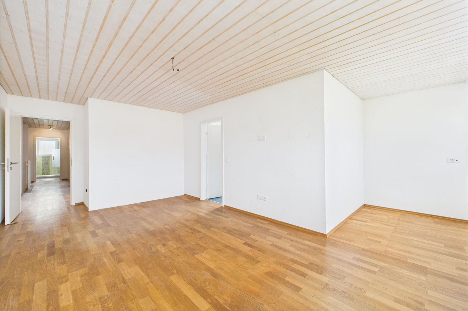 Heller leerer Innenraum mit Holzdecke und Parkettboden