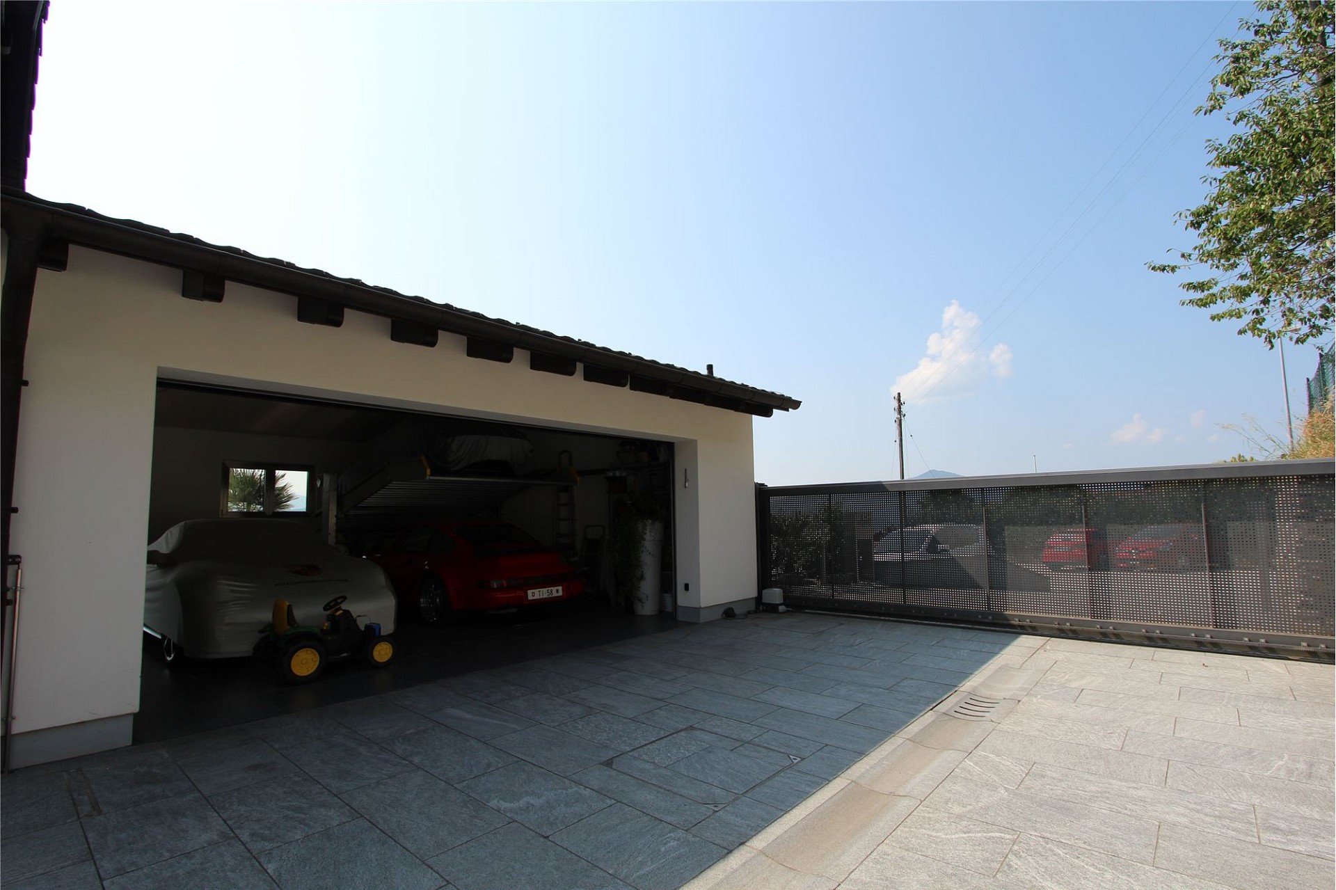 Moderne Einfahrt mit Garage und gepflasterter Terrasse