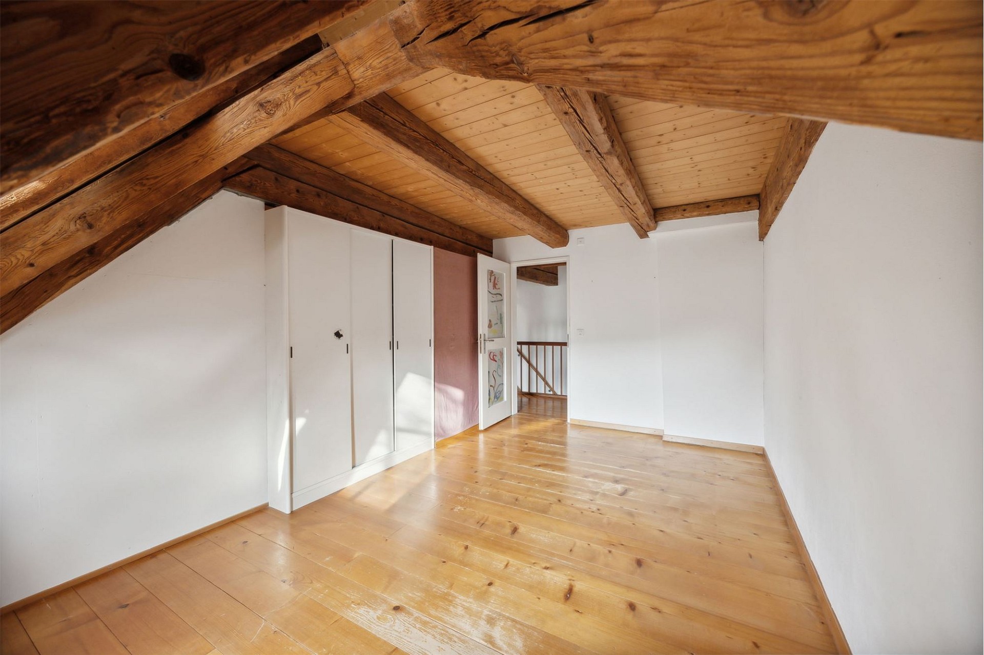 Dachgeschosszimmer mit Holzbalken und Einbauschrank