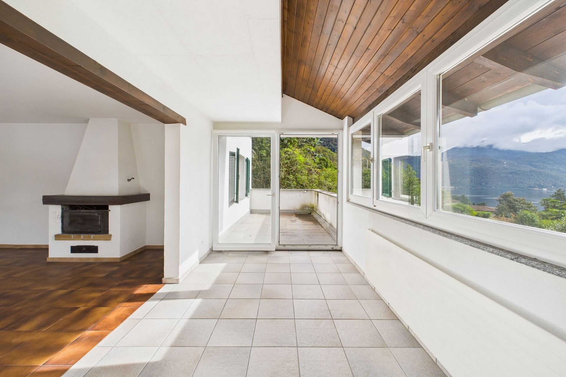 Heller Wohnraum mit Kamin und großer Fensterfront zum Balkon