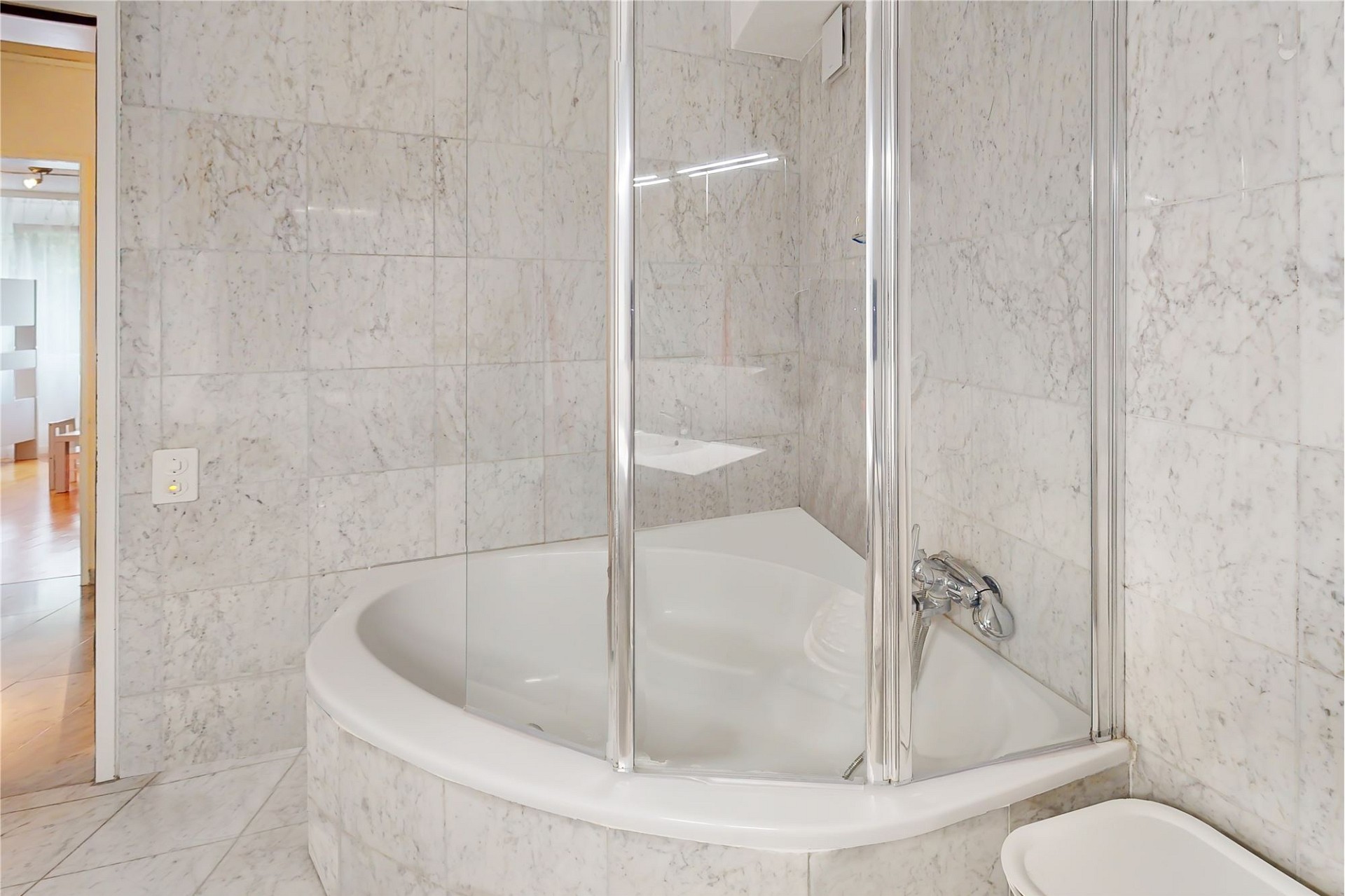 Badezimmer mit Eckbadewanne und Marmorfliesen