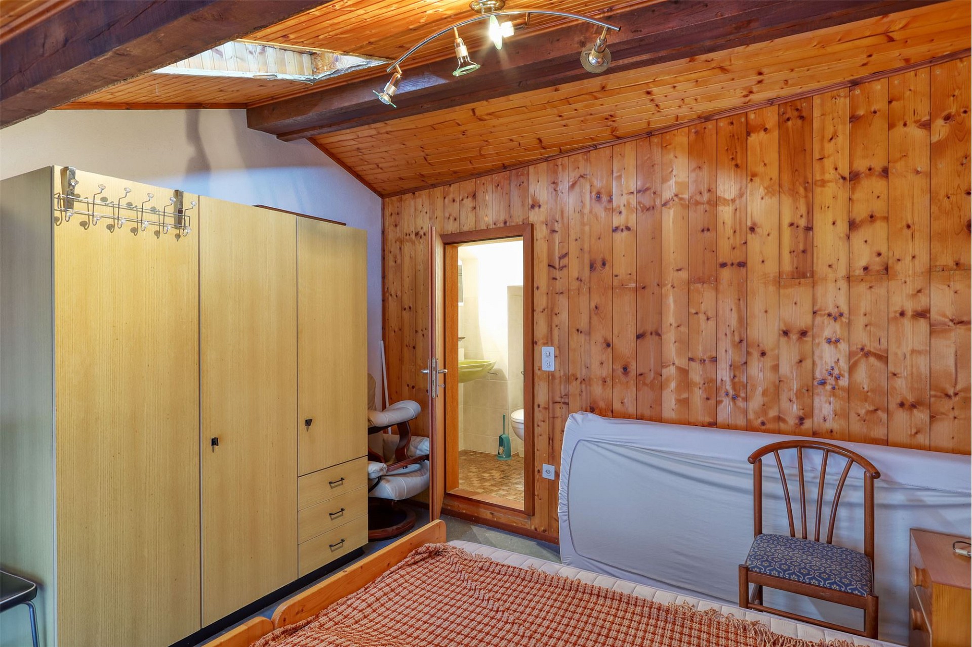 Holzvertäfeltes Schlafzimmer mit offenem Badzugang