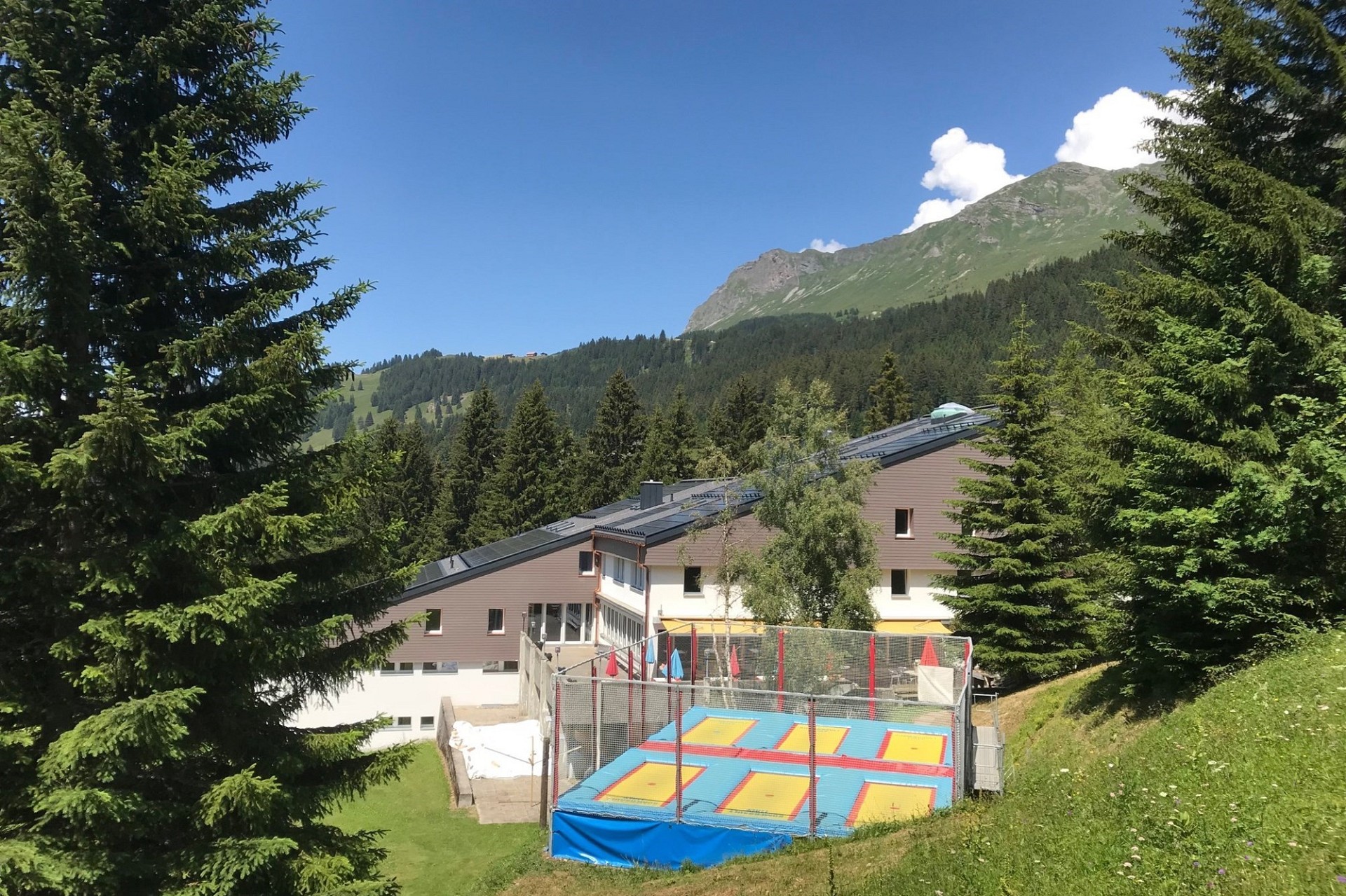 Berghaus mit Spielbereich im alpinen Umfeld