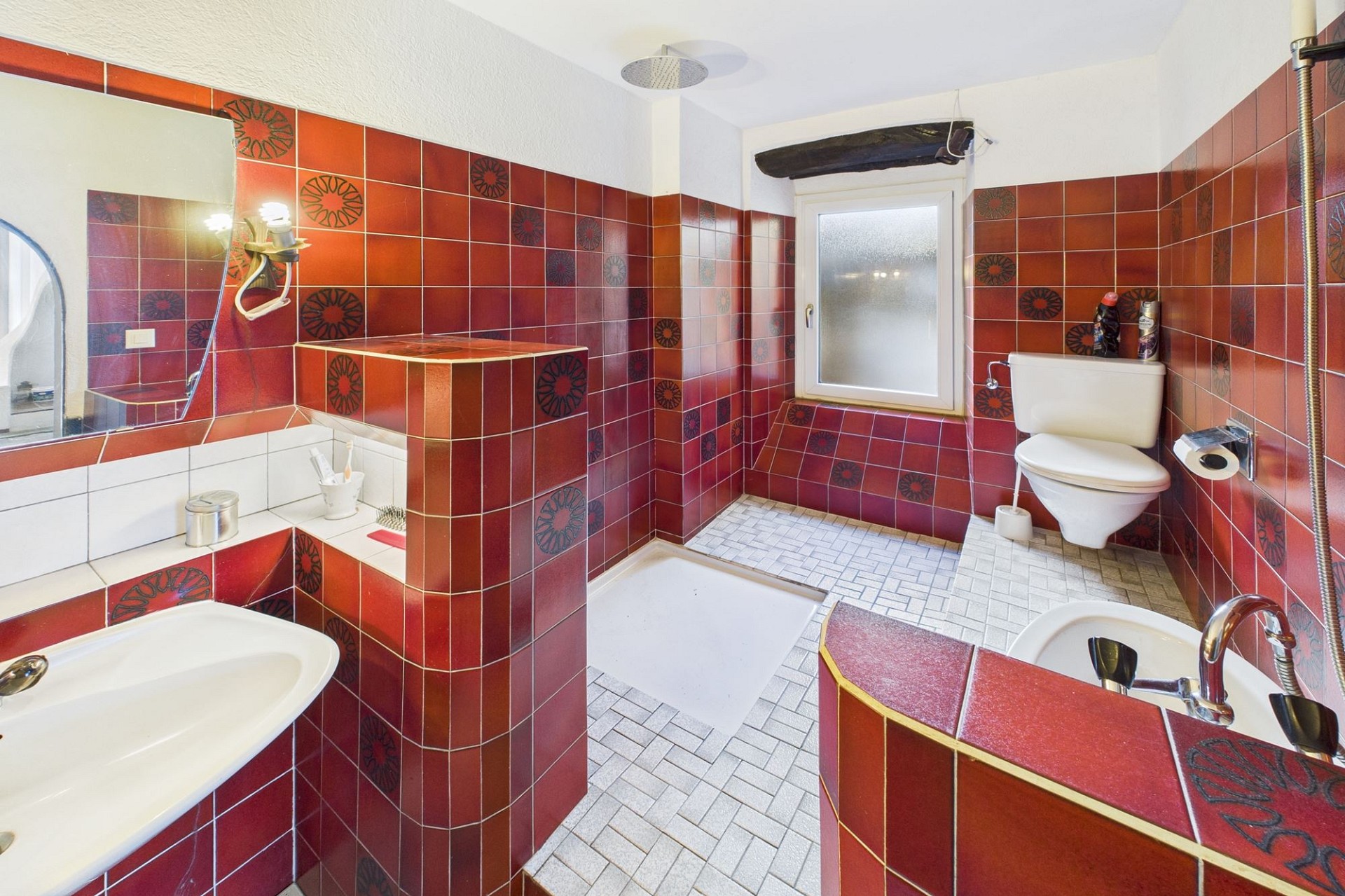 Badezimmer mit rot gefliesten Wänden und WC
