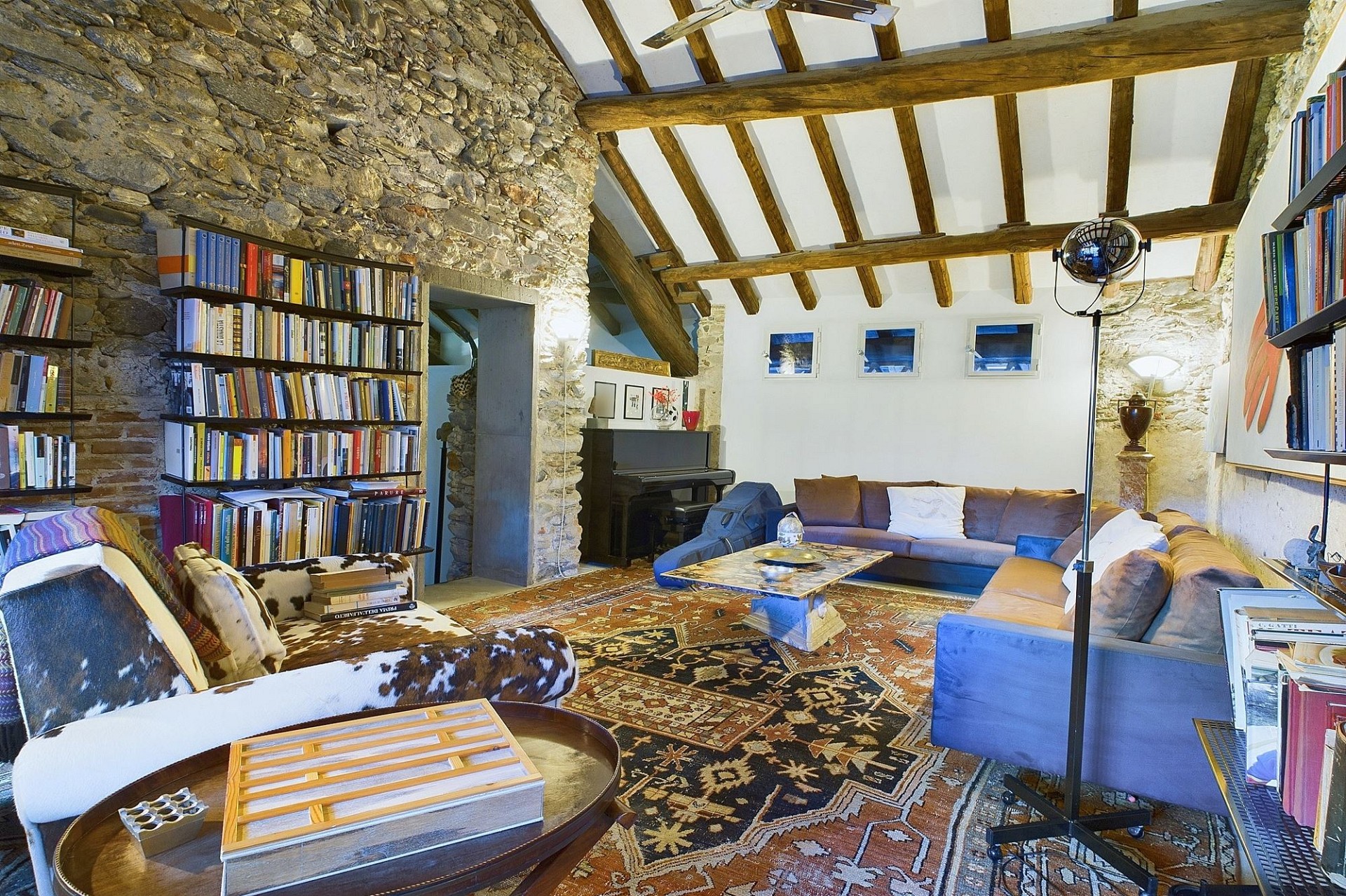 Gemütliches rustikales Wohnzimmer mit Steinwand und Holzbalkendecke