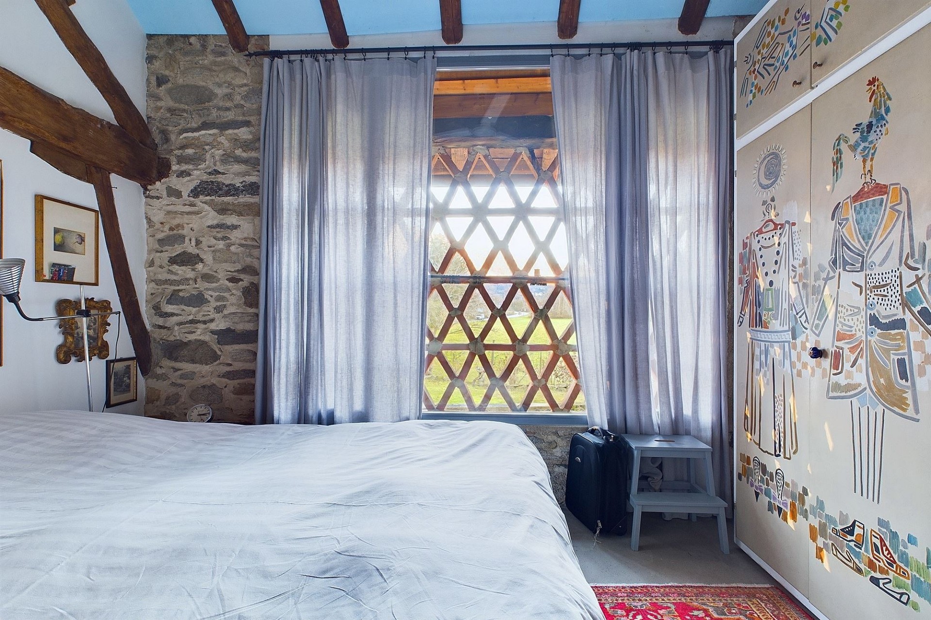 Rustikales Schlafzimmer mit Natursteinwand und Holzbalken