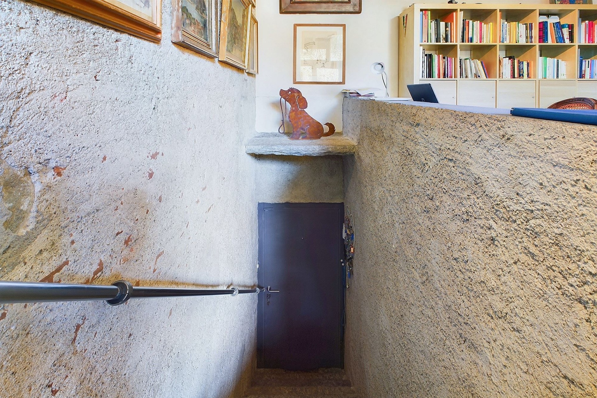 Treppenhaus mit Steinwänden und Bücherregal