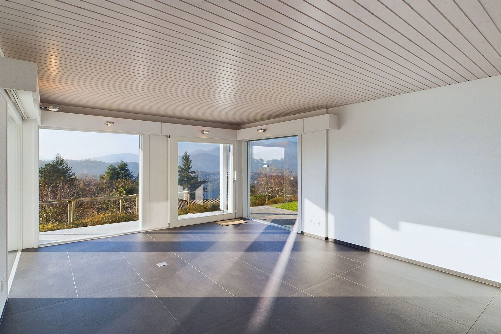 Heller leerer Wohnraum mit Panoramafenstern und Bergblick
