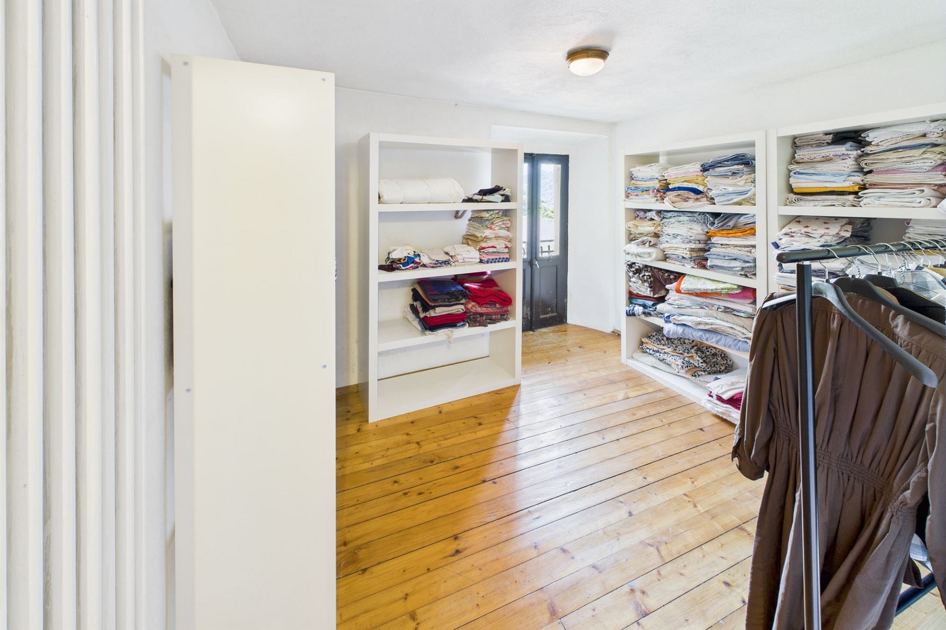 Ankleidezimmer mit weißen Regalen und Holzdielenboden