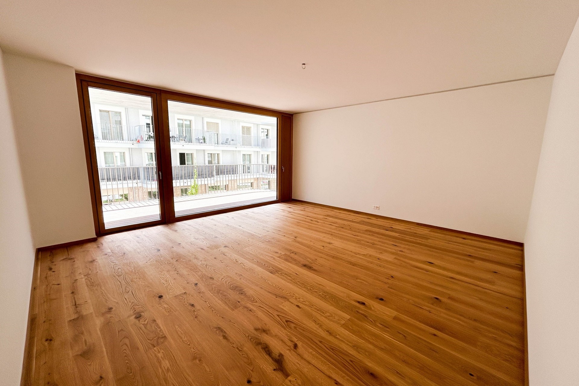 Heller leerer Wohnraum mit Balkon und Holzboden