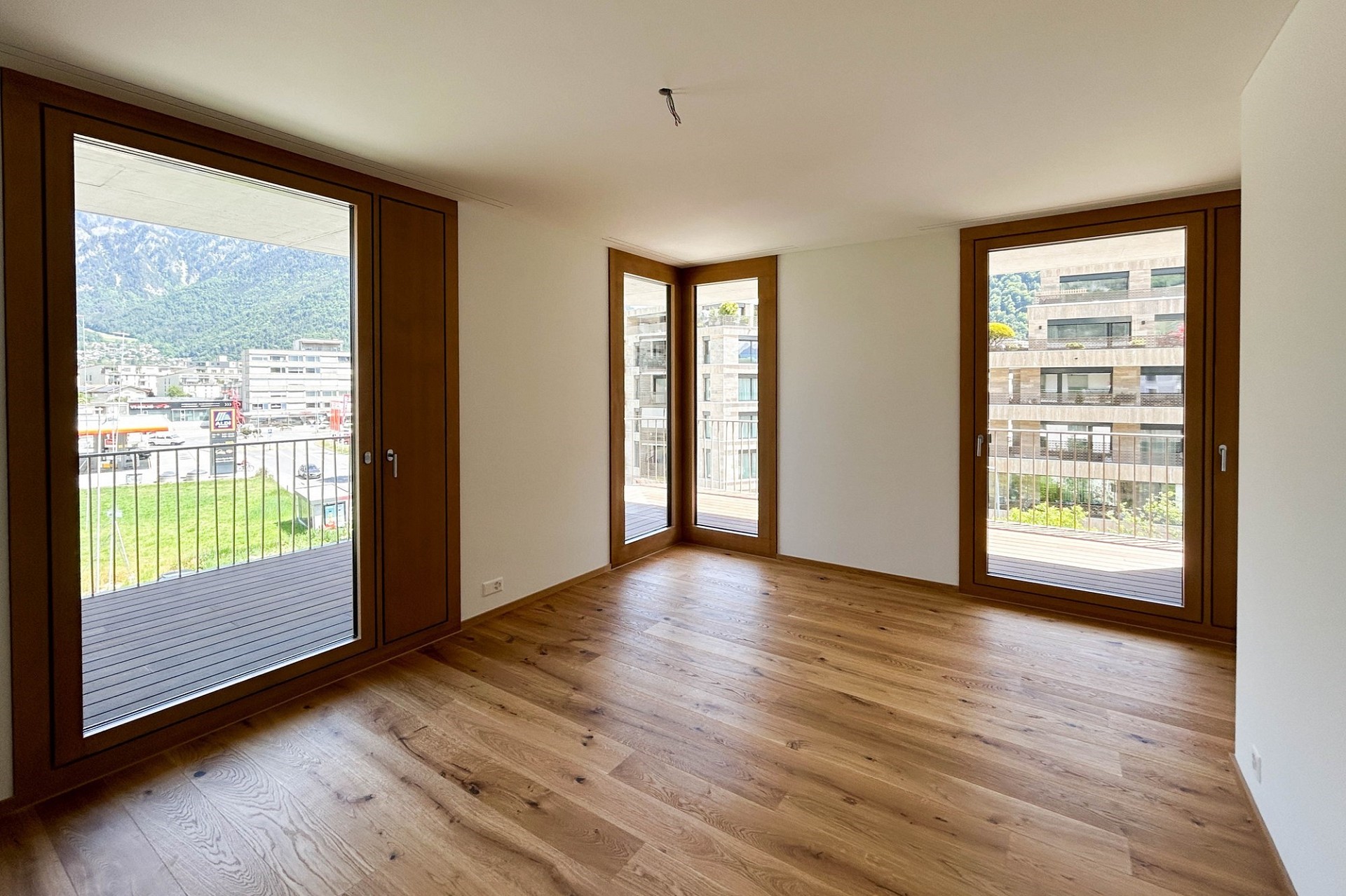 Heller leerer Raum mit Holzboden und großen Fenstertüren