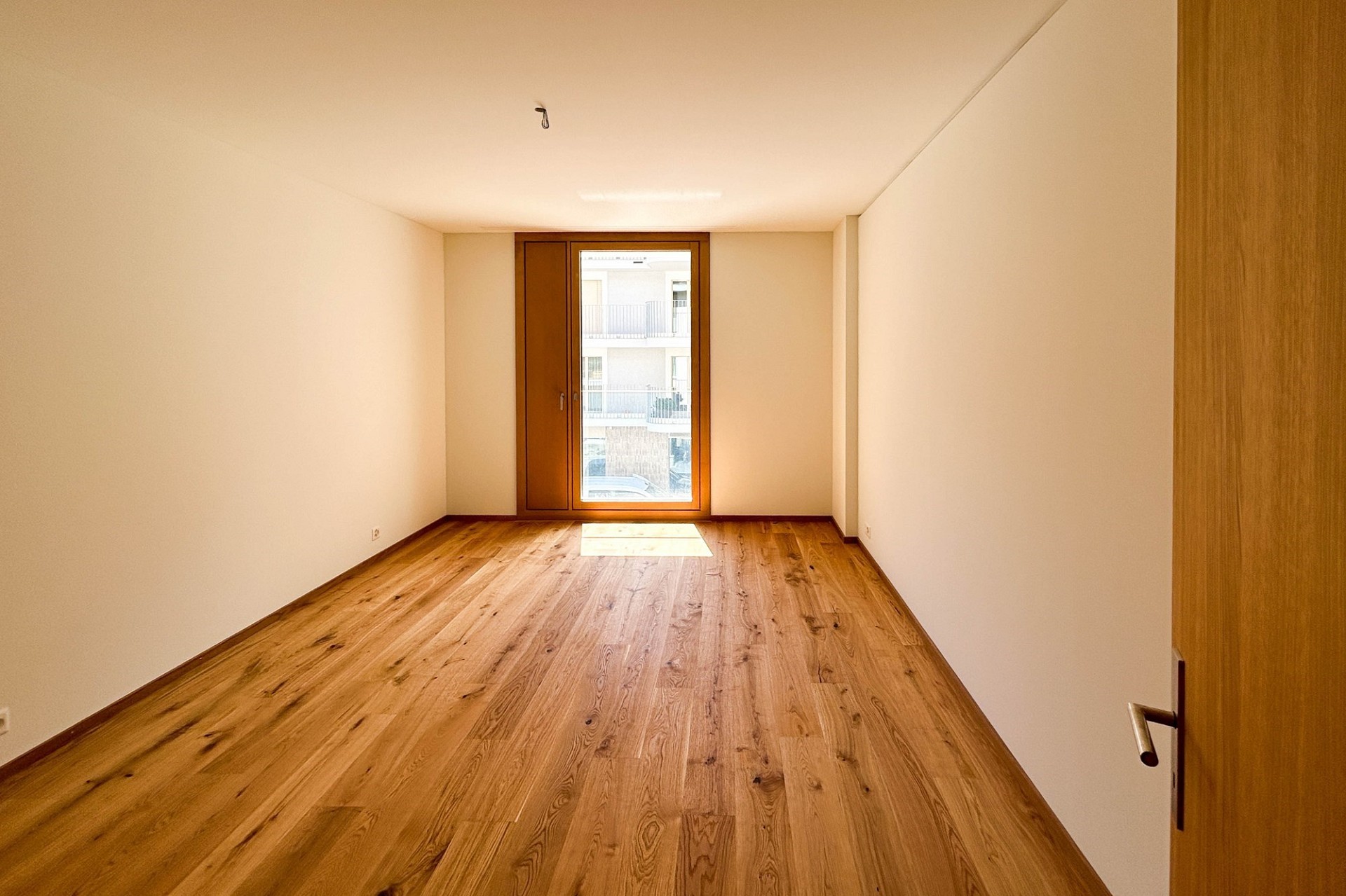 Heller leerer Raum mit Holzparkett und Fenster