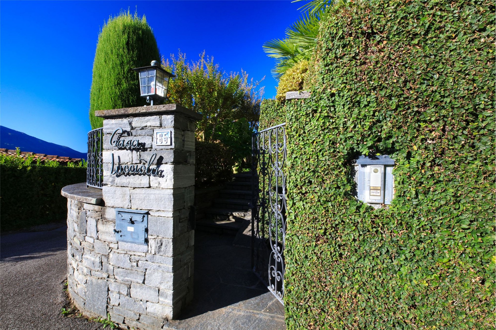 Einfahrt mit Steinpfeiler und Hecke