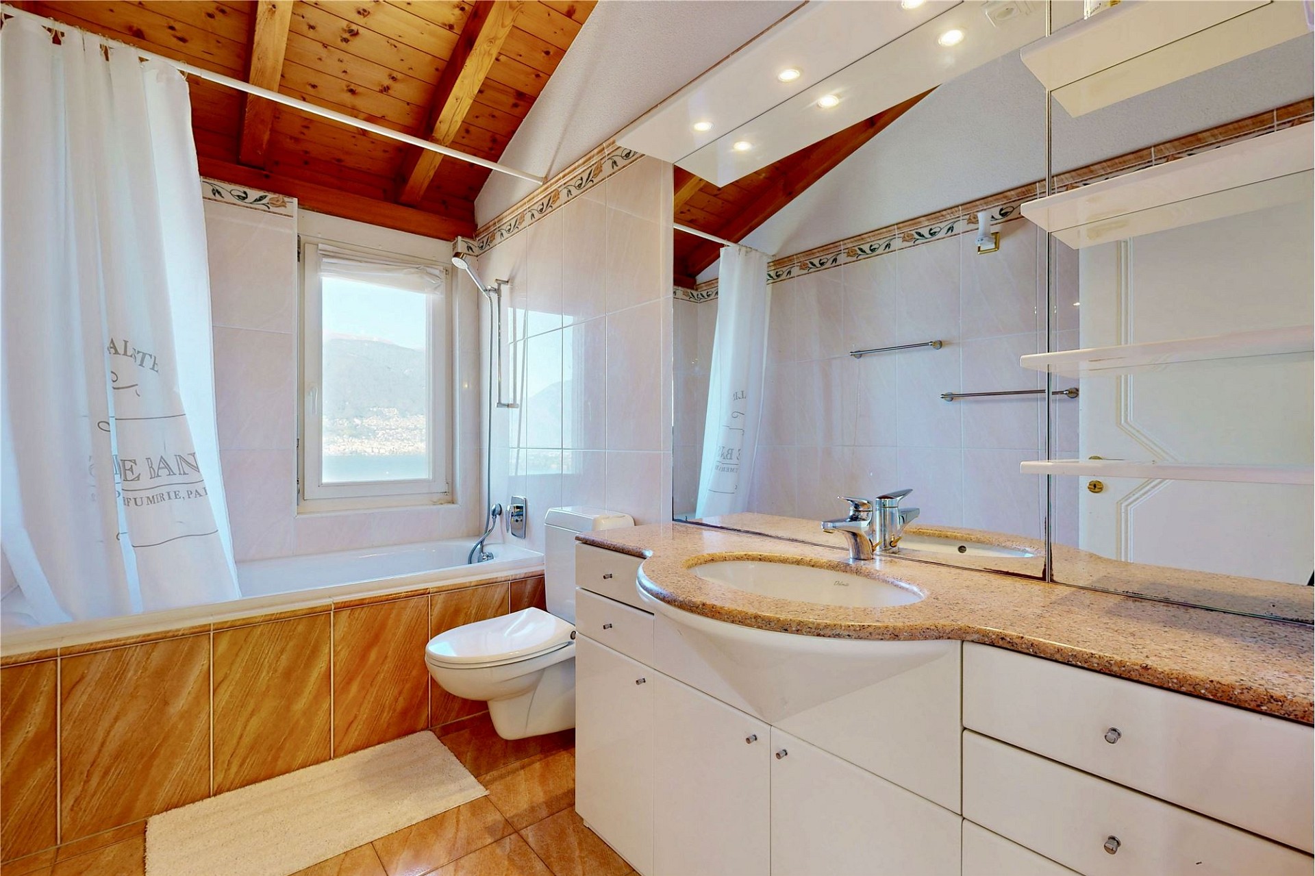 Badezimmer mit Holzdecke und Fensterblick