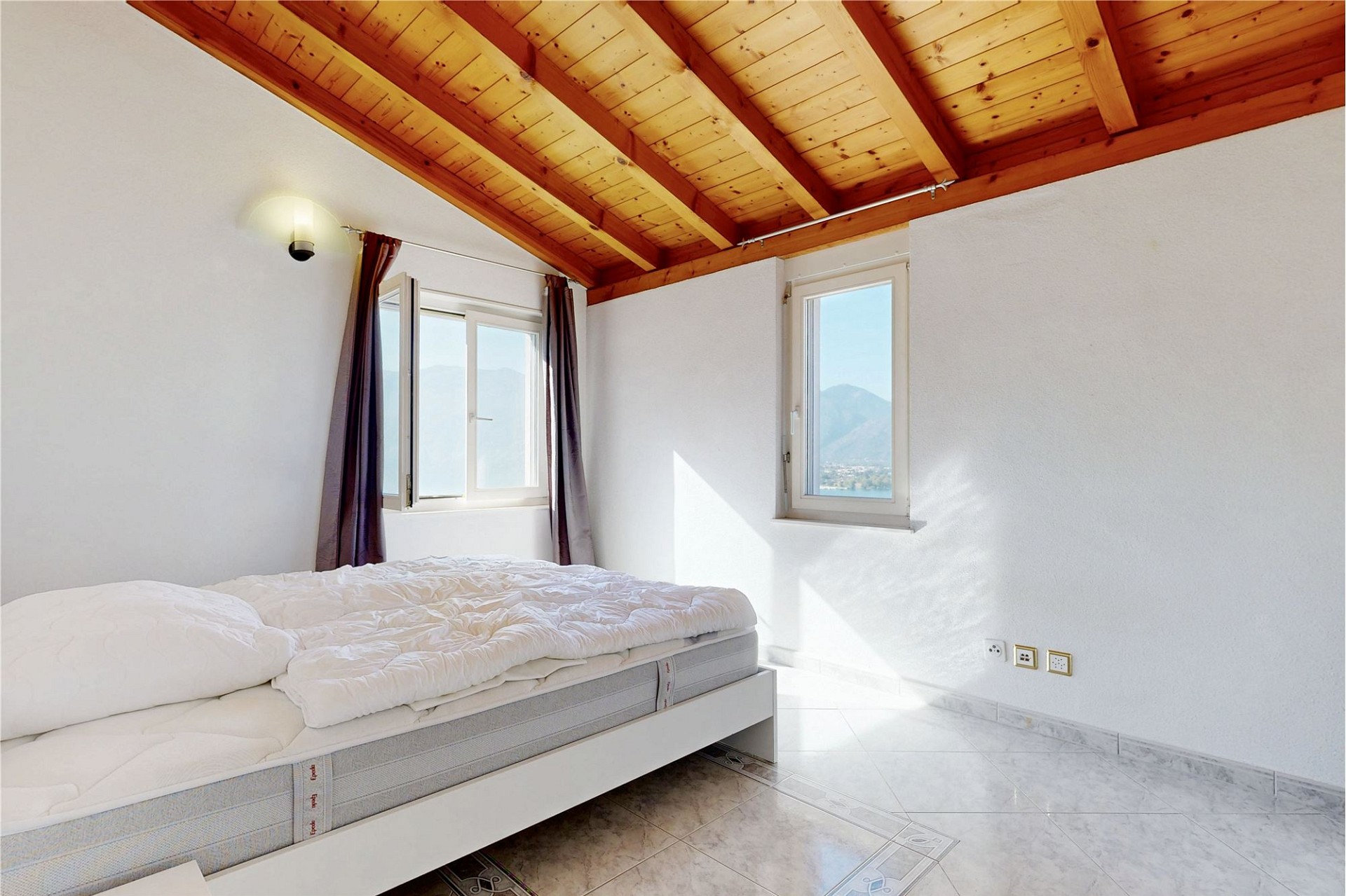 Schlafzimmer mit Holzbalkendecke und Bergblick