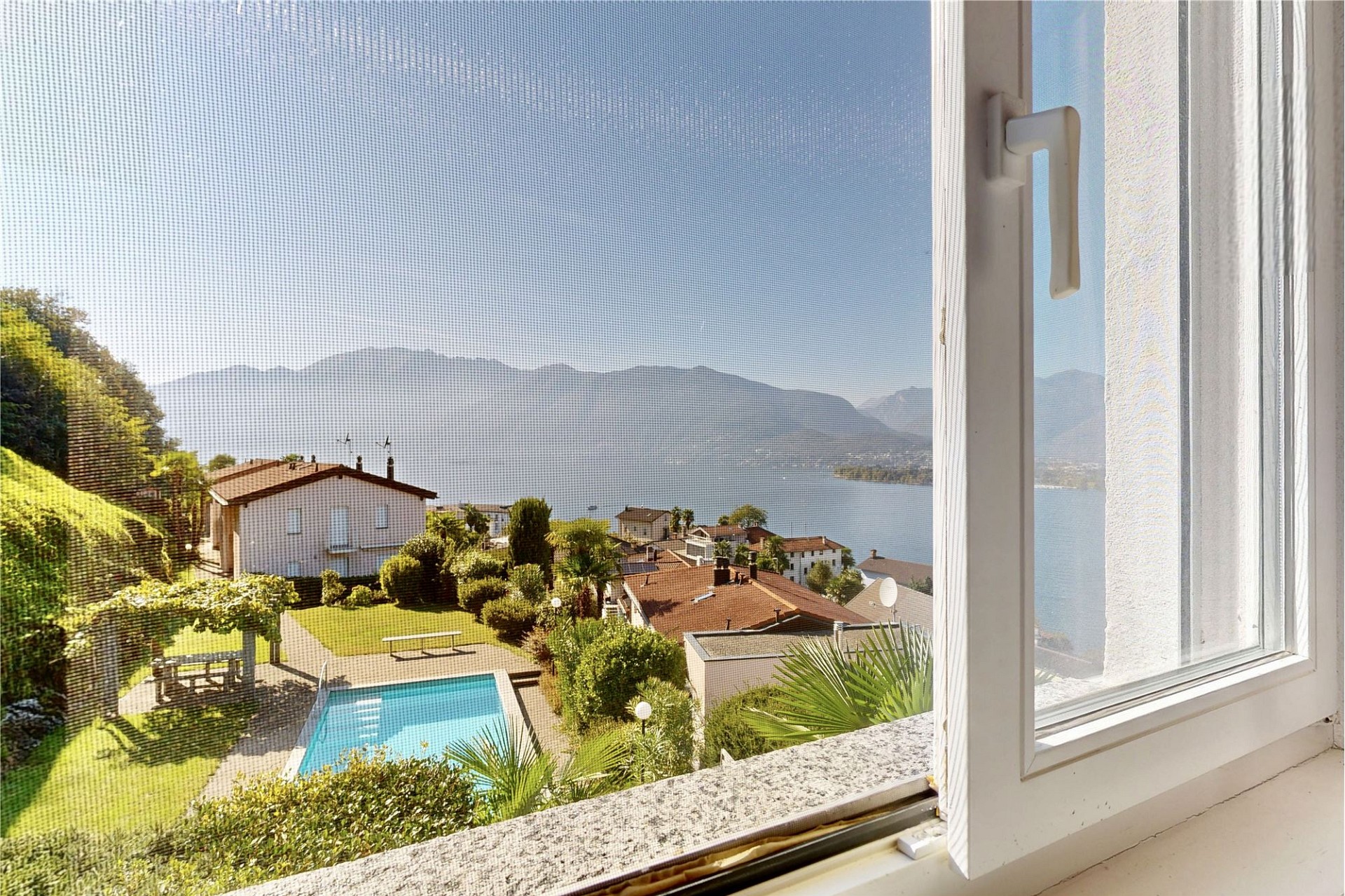 Blick auf See, Berge und Pool durch ein geöffnetes Fenster