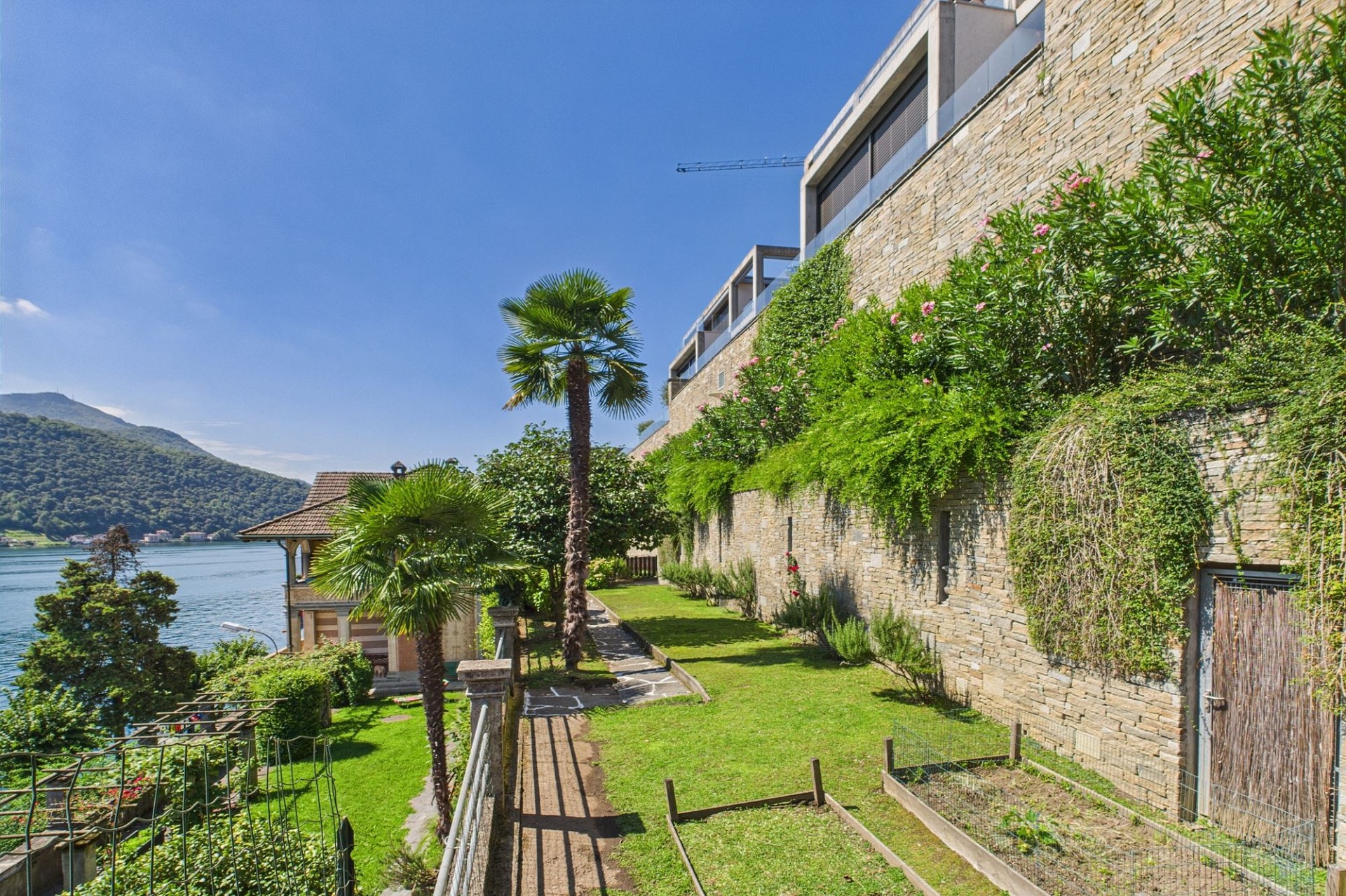 Seeblick mit mediterranem Garten an einer steinverkleideten Luxusimmobilie