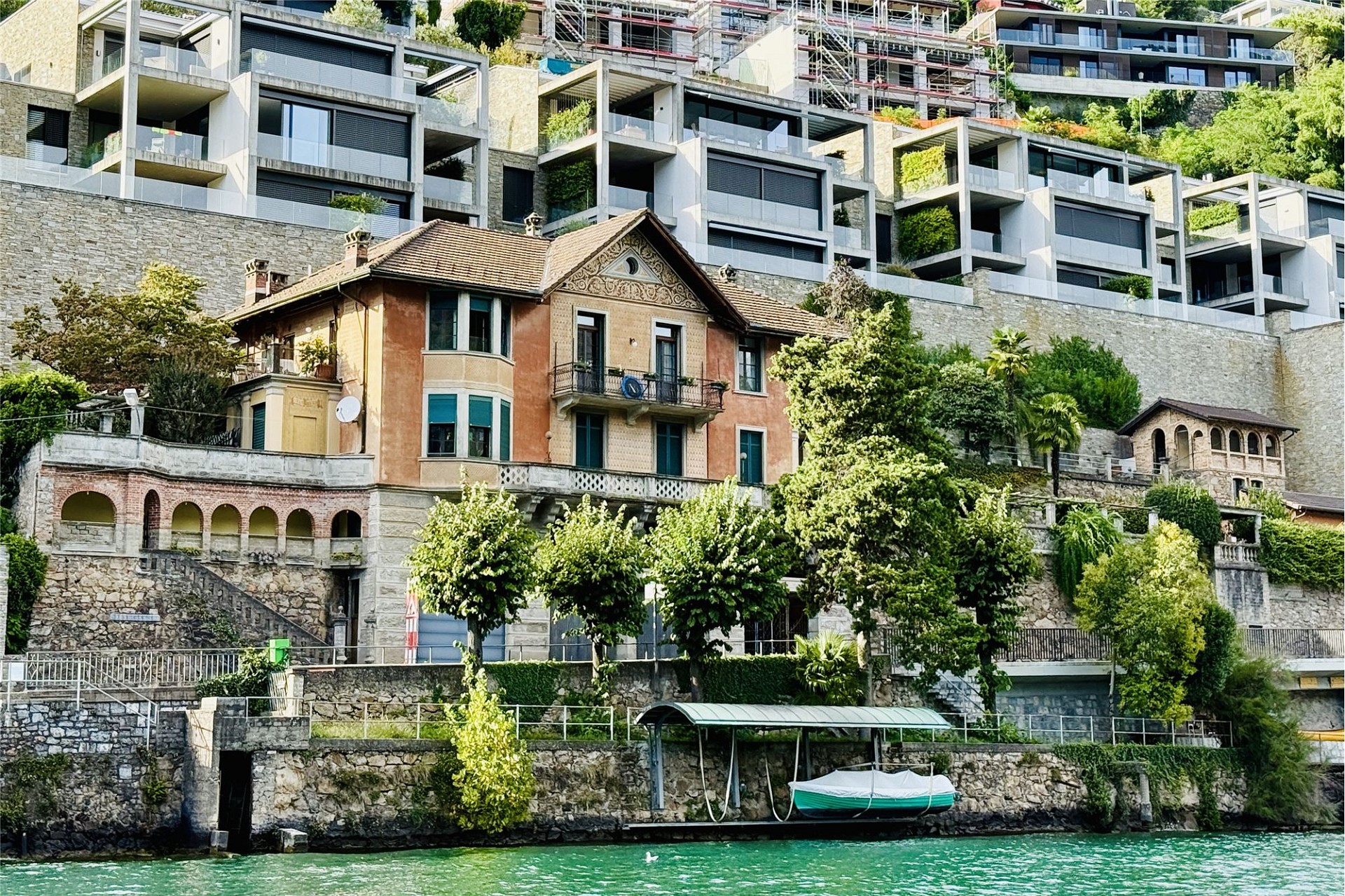 Historisches Haus am Wasser mit Terrassenhang und moderner Nachbarbebauung