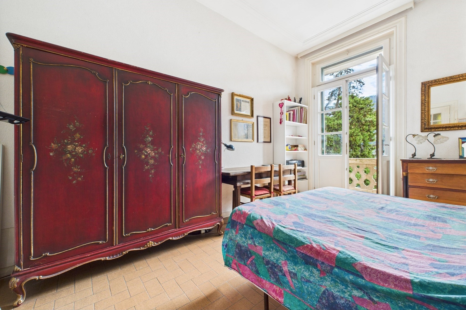 Schlafzimmer mit antikem Kleiderschrank und offenem Balkonfenster