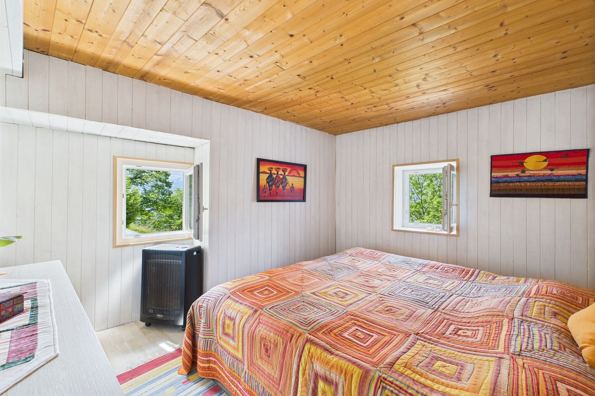 Helles Schlafzimmer mit Holzdecke und Blick ins Grüne
