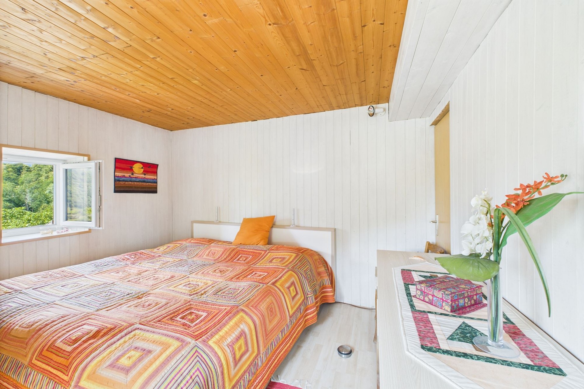 Helles Schlafzimmer mit Holzdecke und Gartenblick