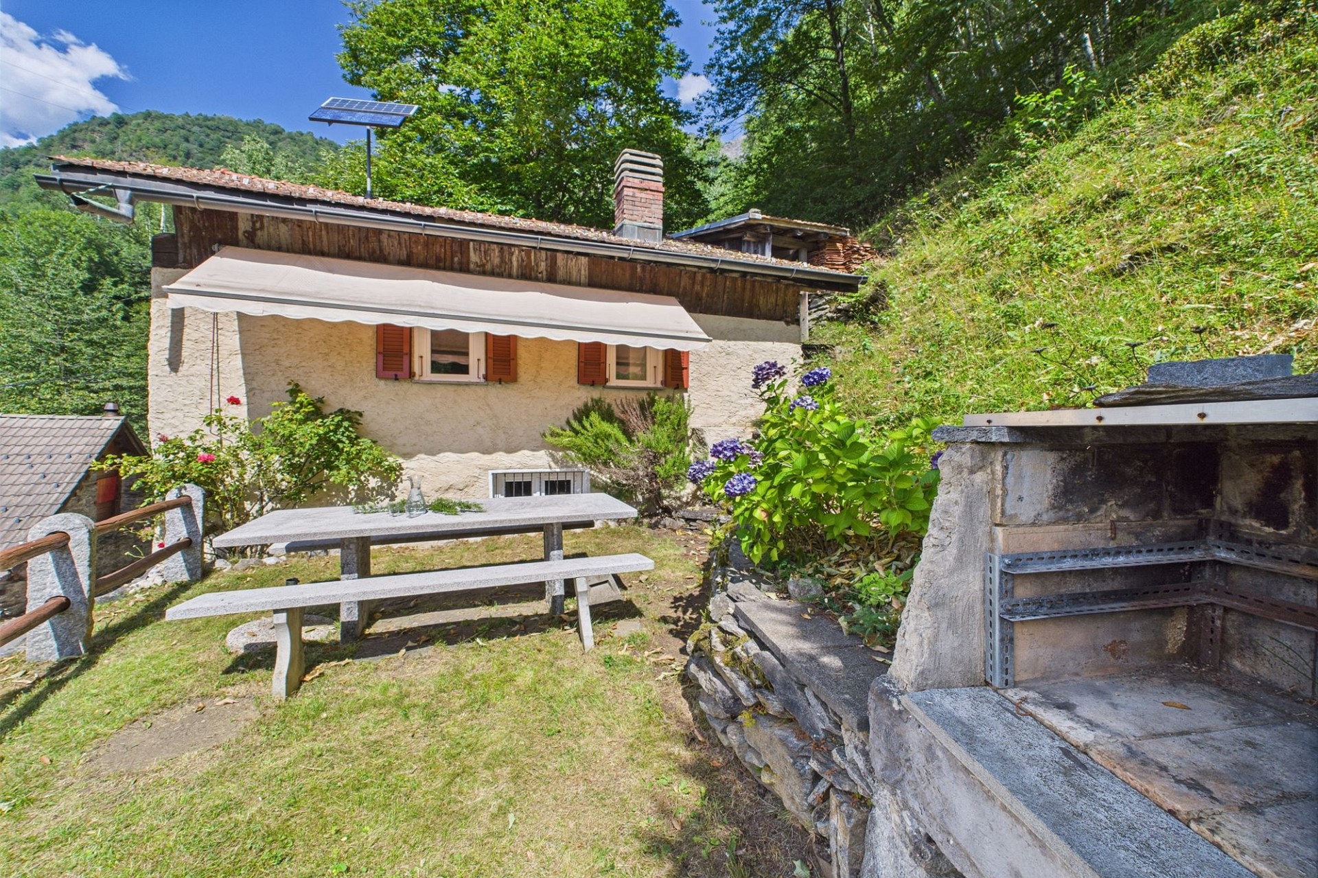 Berggarten mit rustikalem Haus und Grillplatz