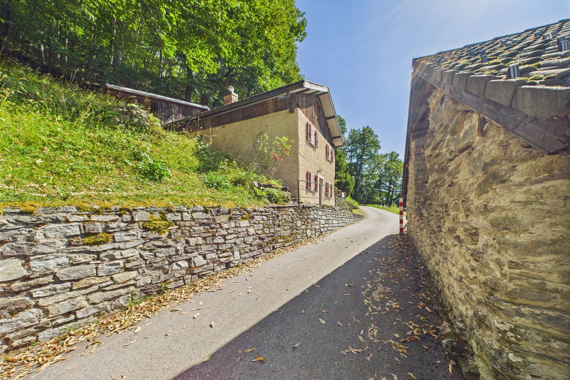 Ländliche Zufahrt mit Steinhaus und Hanglage
