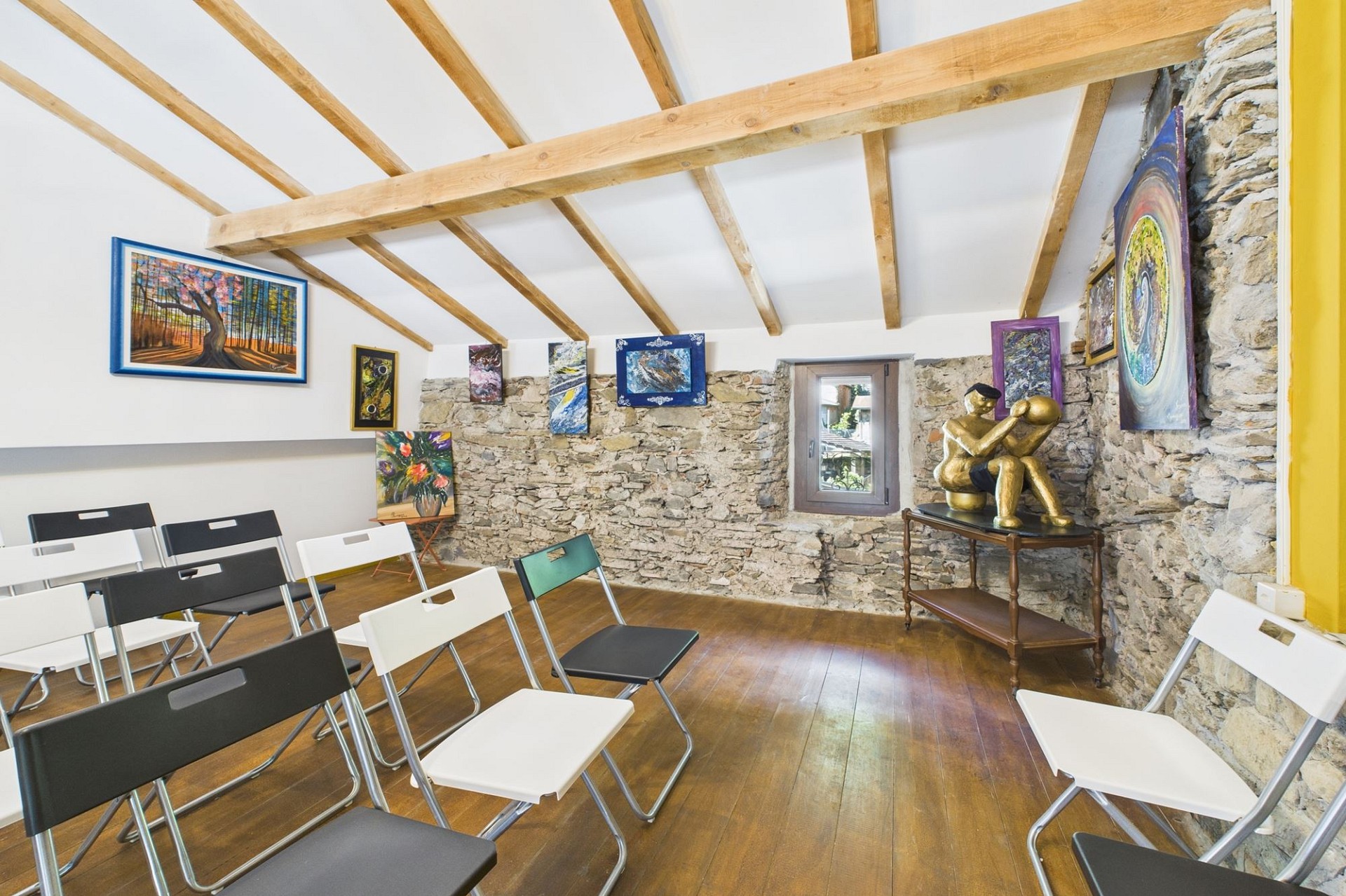 Kleiner Ausstellungsraum mit Natursteinwand und Holzbalkendecke
