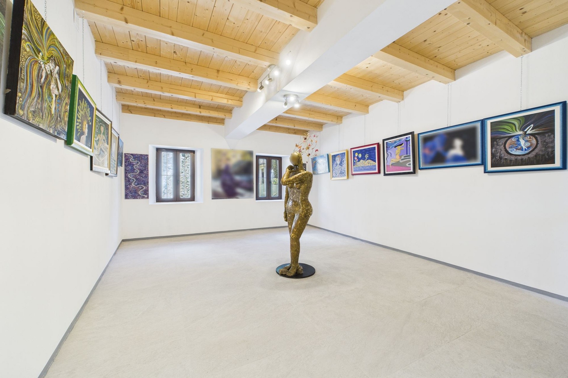 Kunstgalerie mit sichtbaren Skulpturen und Holzdecke