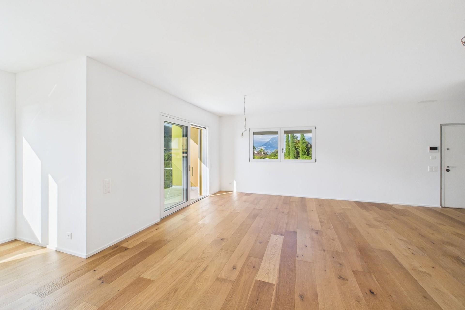 Heller leerer Wohnraum mit Parkett und Ausblick