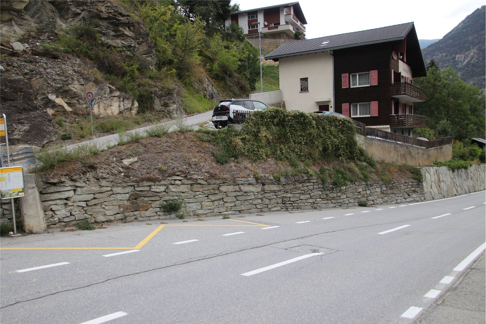 Alpenhaus an Hanglage an einer Straße