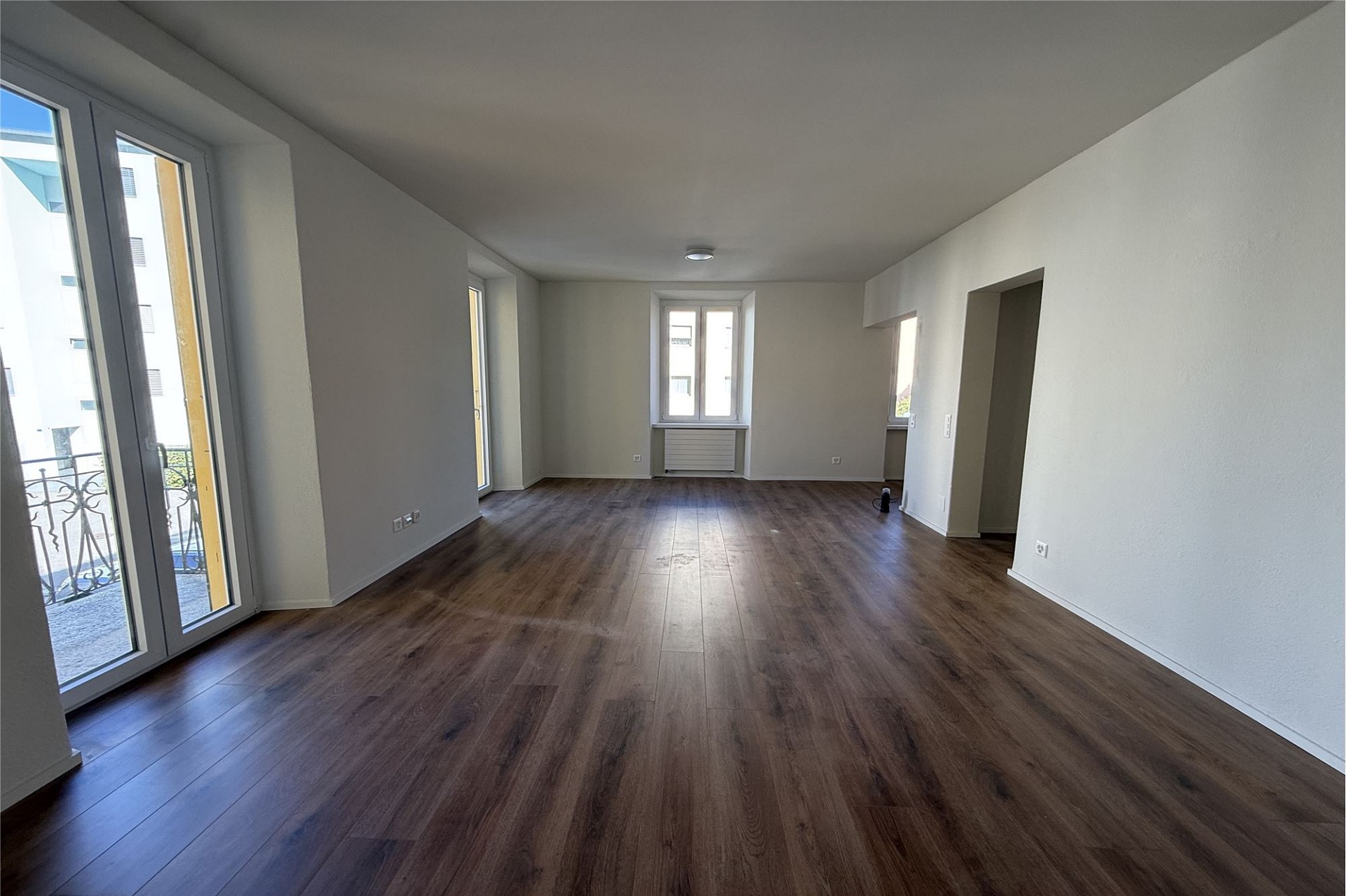 Helles, leeres Wohn-/Esszimmer mit Balkon
