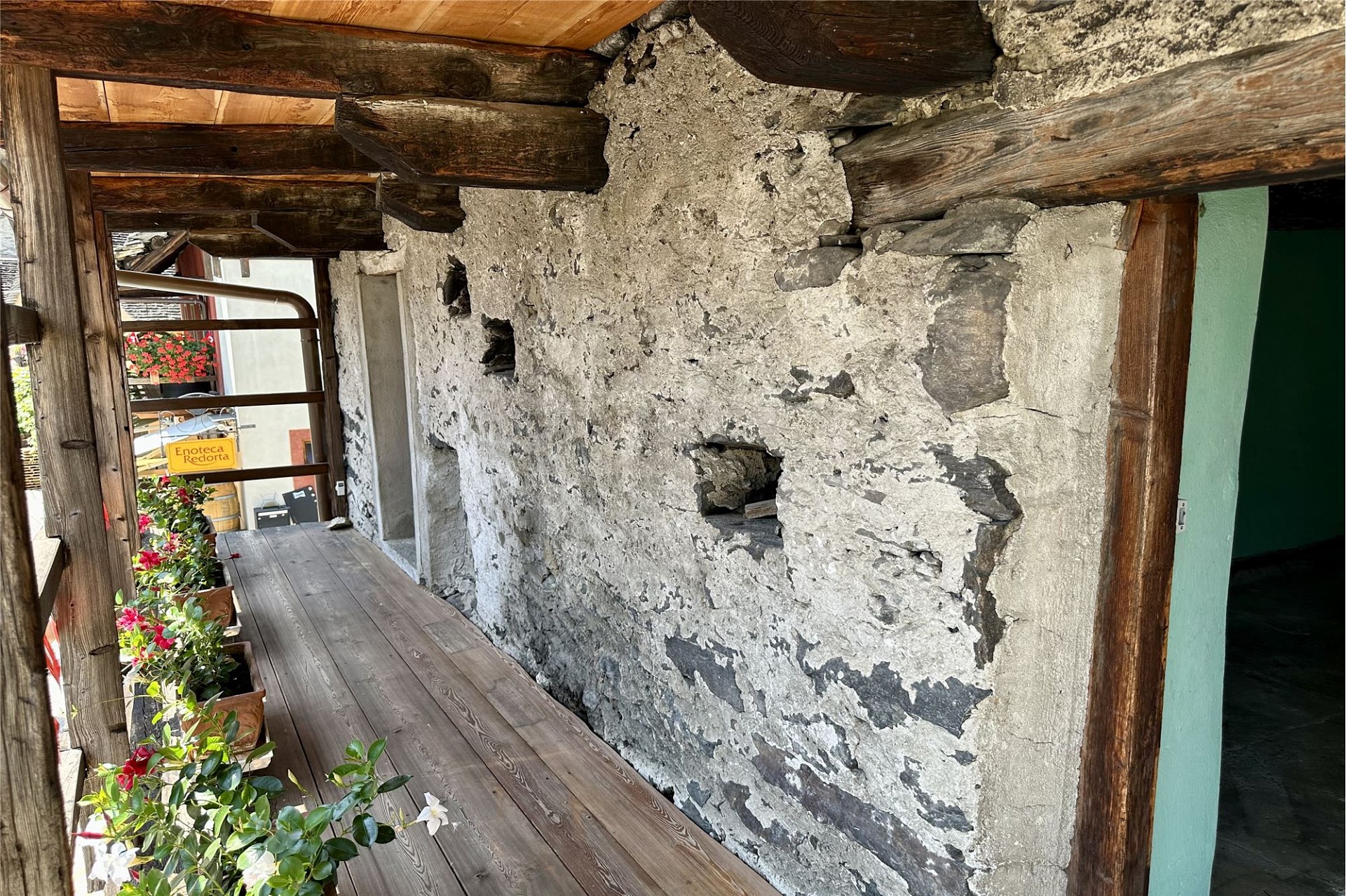 Überdachter Außengang mit rustikaler Steinwand