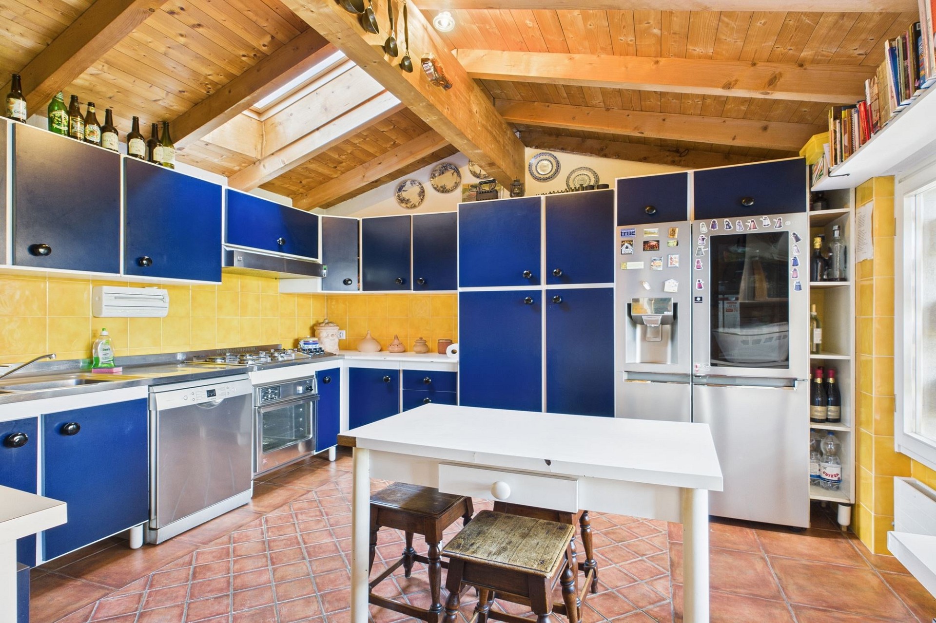 Küche mit rustikalem Holzdach und blauen Fronten