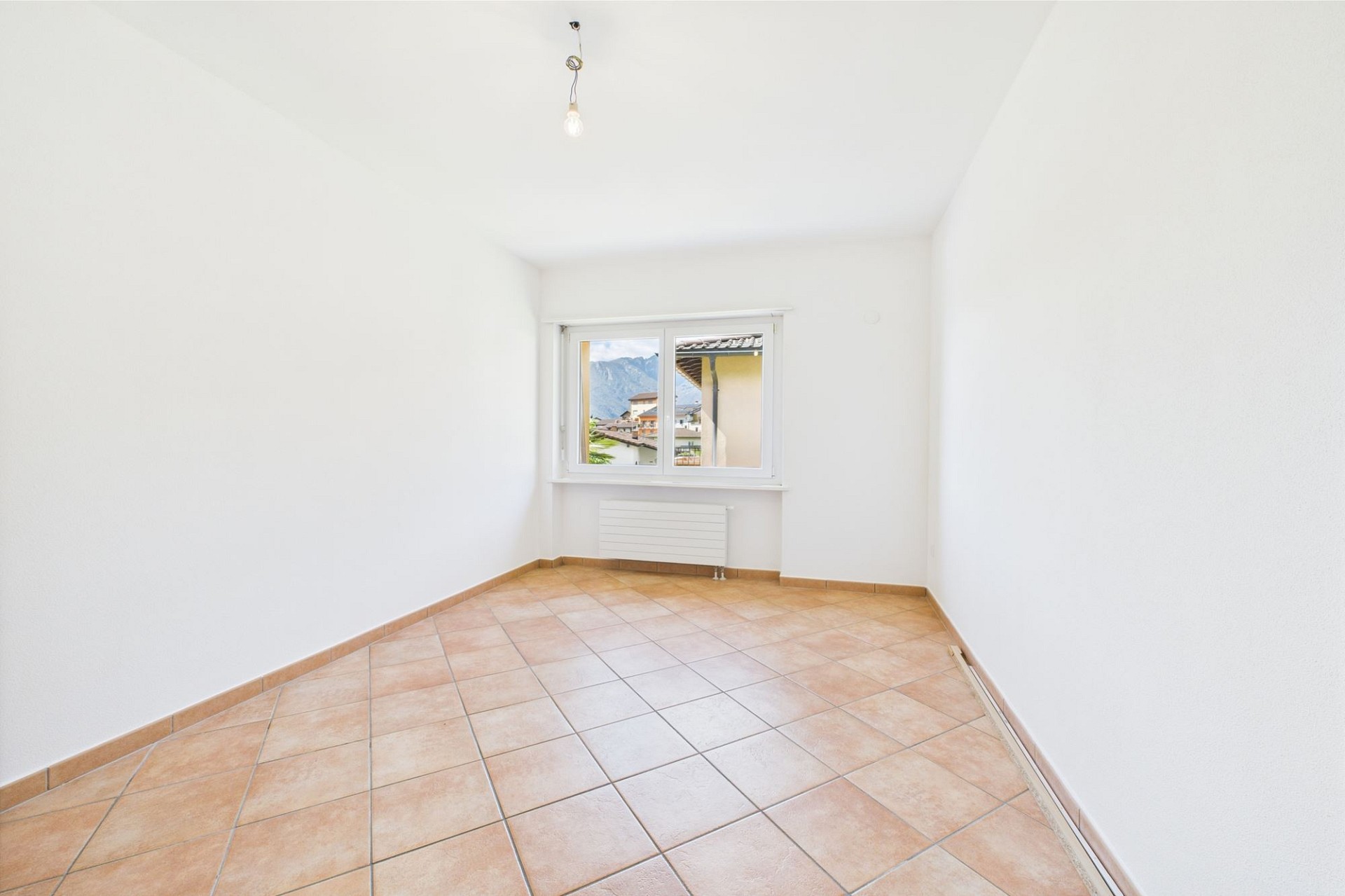 Heller leerer Raum mit Fliesenboden und Fensterblick