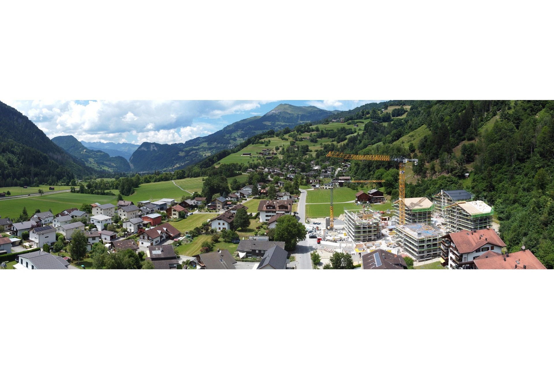 Alpine Tal- und Berglandschaft mit Dorf und Baustelle