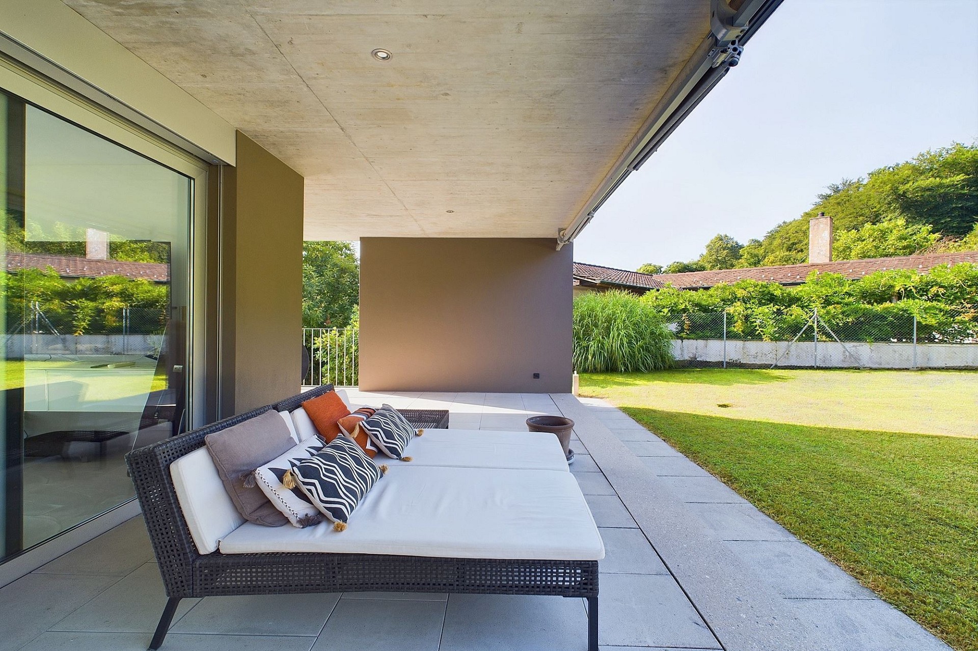 Überdachte Terrasse mit Loungemöbeln und Gartenblick