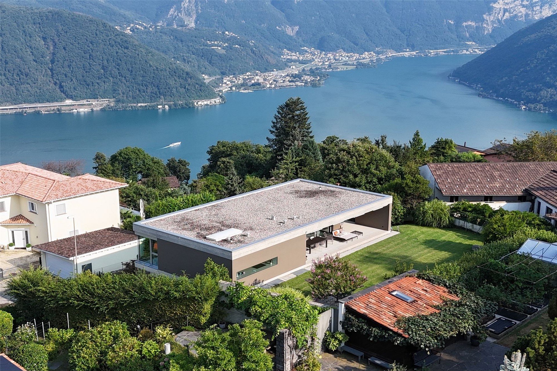 Drohnenaufnahme einer modernen Villa am See mit Garten