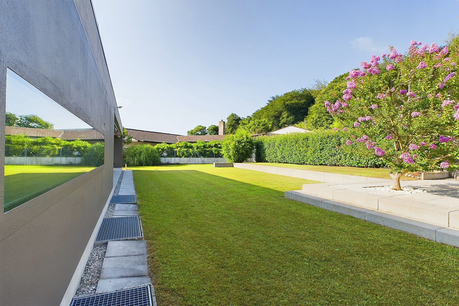 Großer gepflegter Garten neben moderner Hausfassade