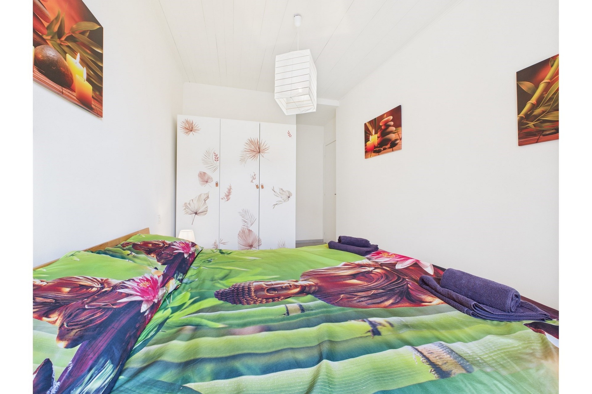 Helles Schlafzimmer mit farbigem Bettbezug und weißem Kleiderschrank